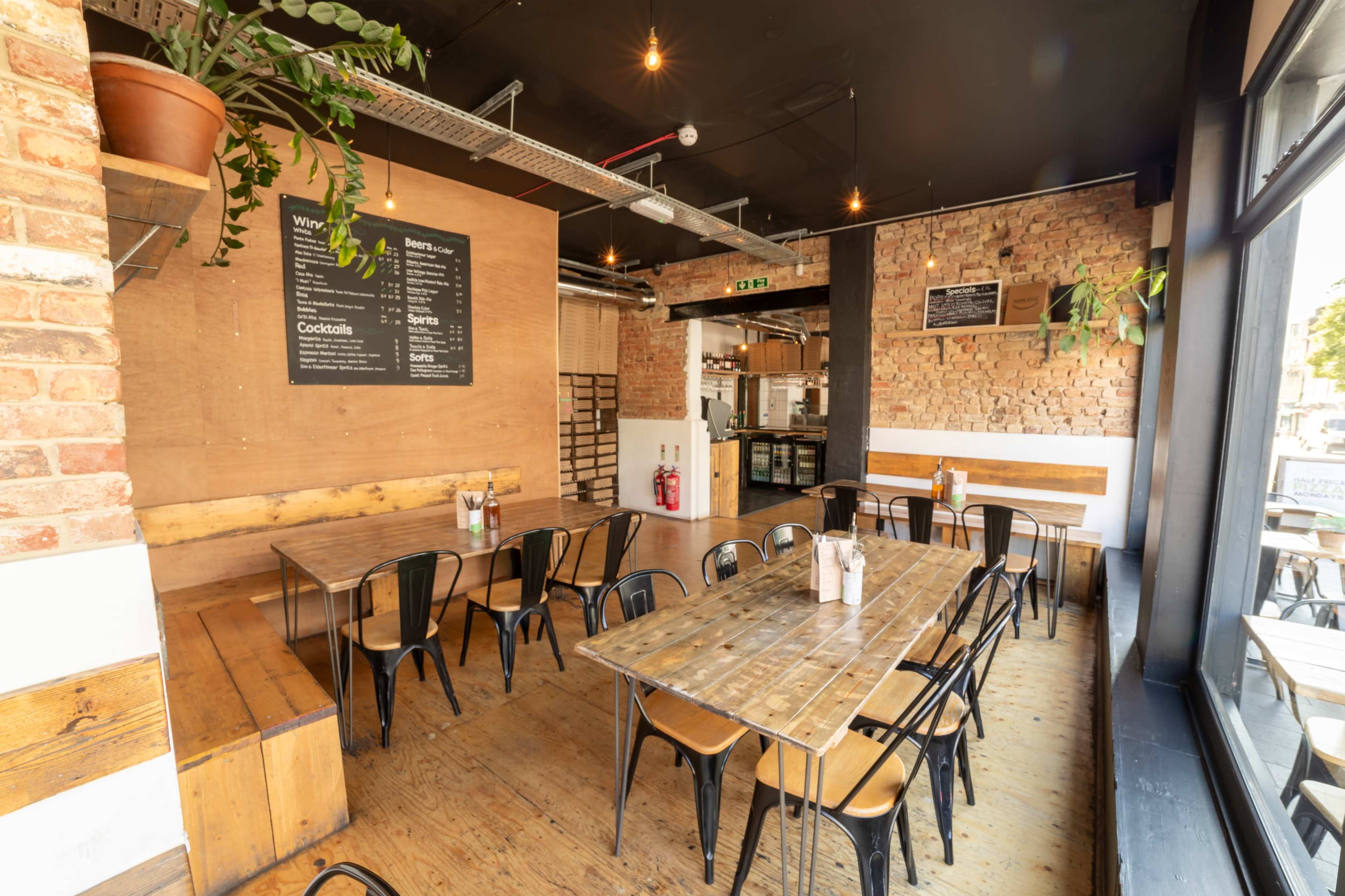 Rustic pizza restaurant with high ceilings and windows spanning the venue. Image in South Norwood, London, ENG