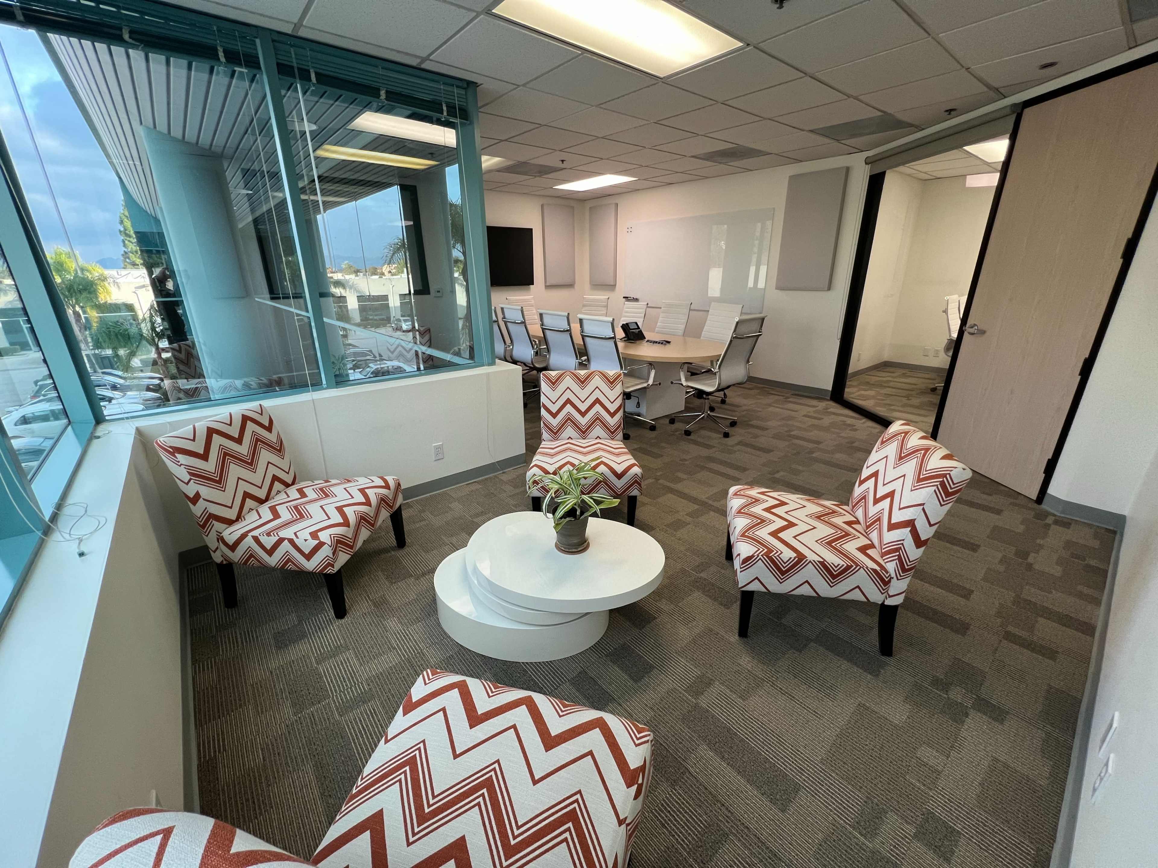 A seating area with patterned chairs surrounds a circular table in an office conference room.