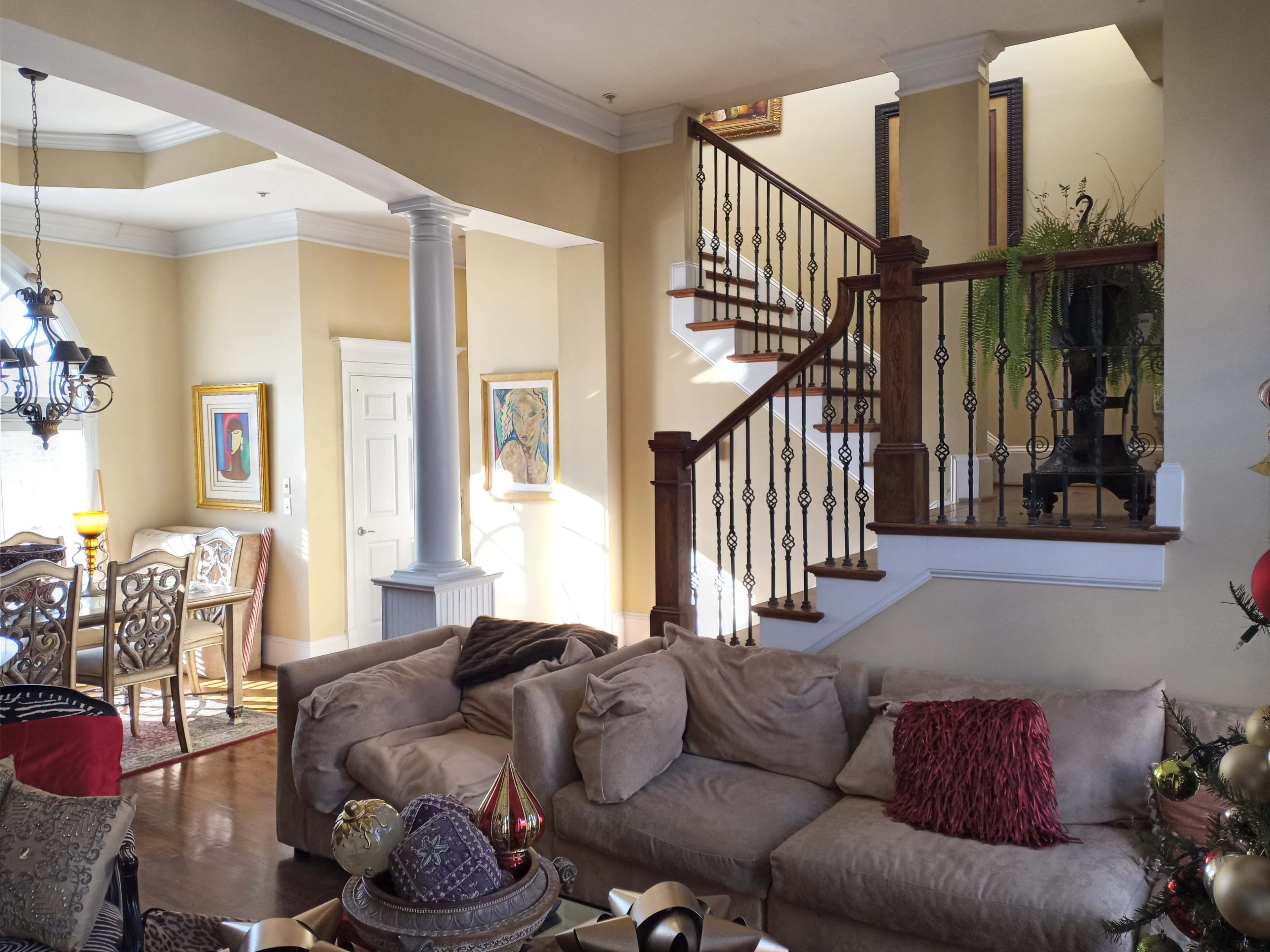A cozy living room features a sectional sofa, elegant dining area, and a staircase leading to an upper level.