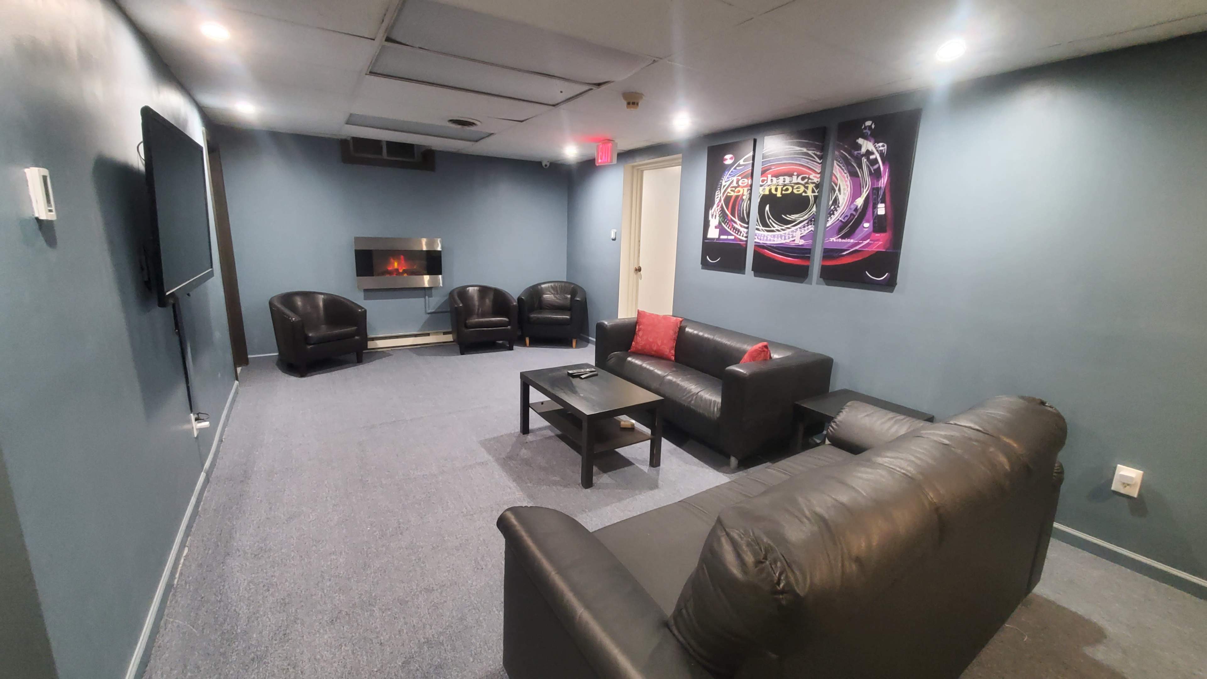 A lounge area with a sofa, chairs, a coffee table, and a wall-mounted television.