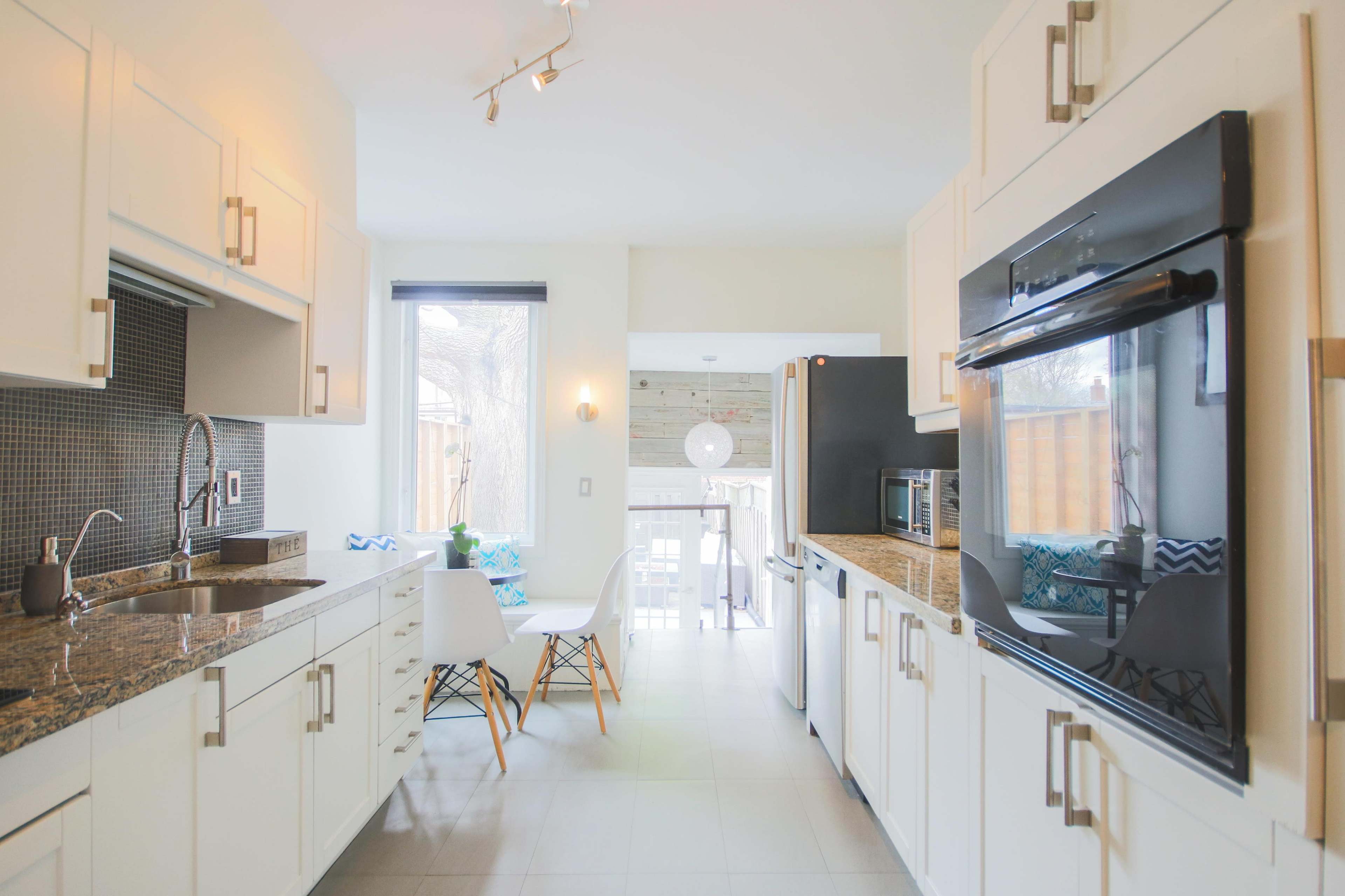 A bright kitchen features white cabinetry, granite countertops, and a dining area with a view of an outdoor space.