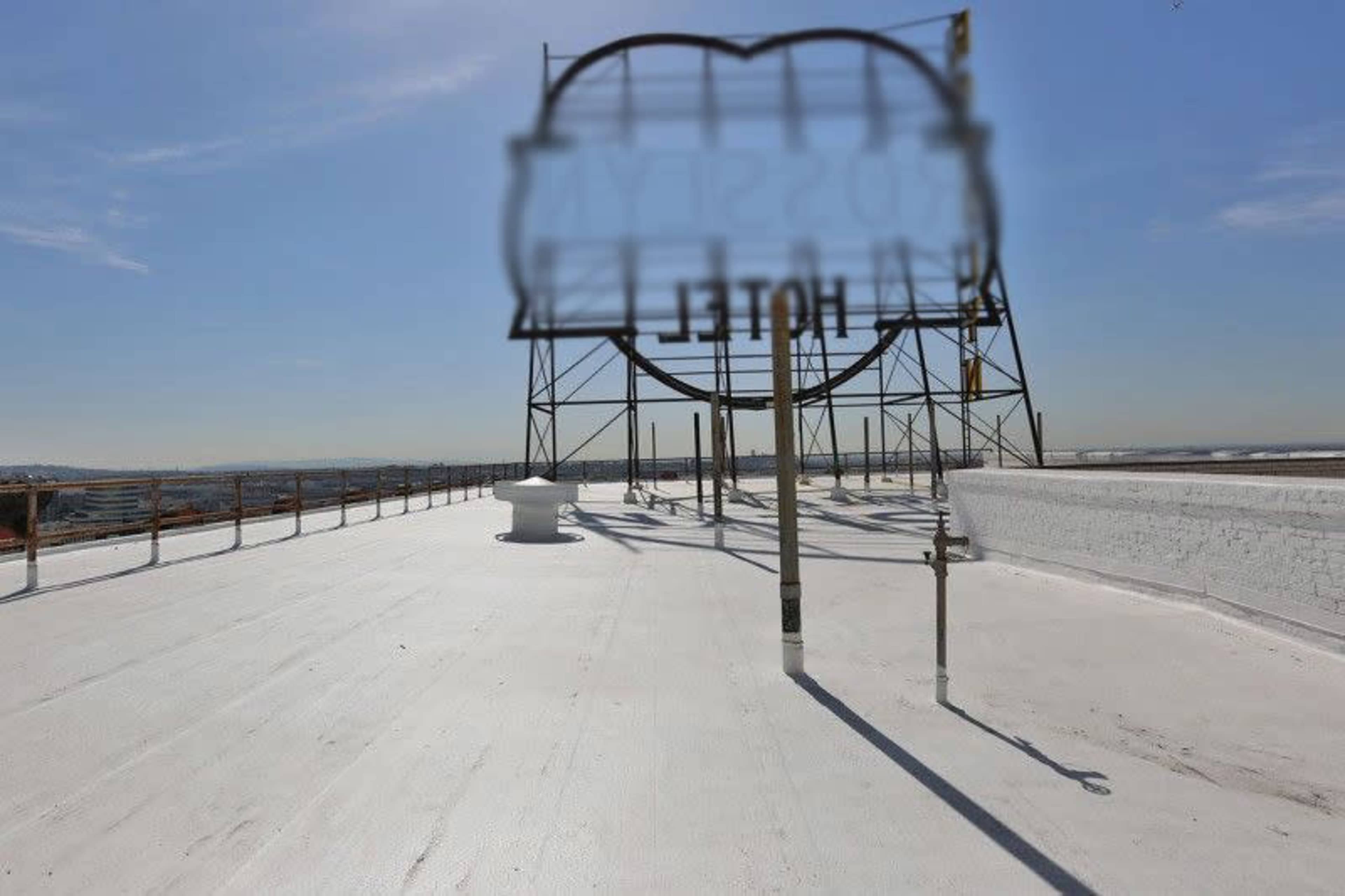 A flat rooftop with a large, partially obscured hotel sign and a clear sky in the background.