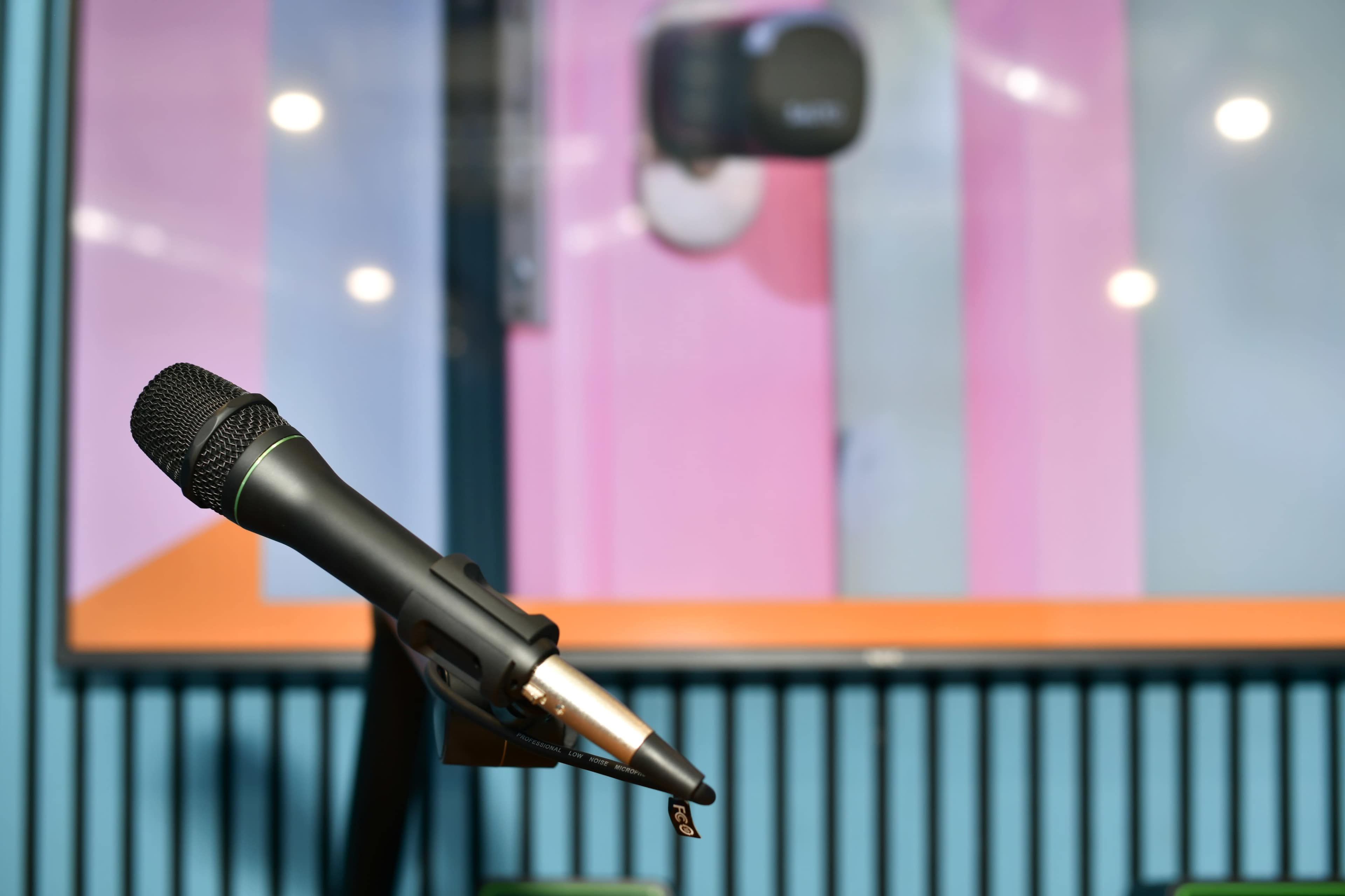 A microphone is positioned in the foreground in front of a colorful wall display.