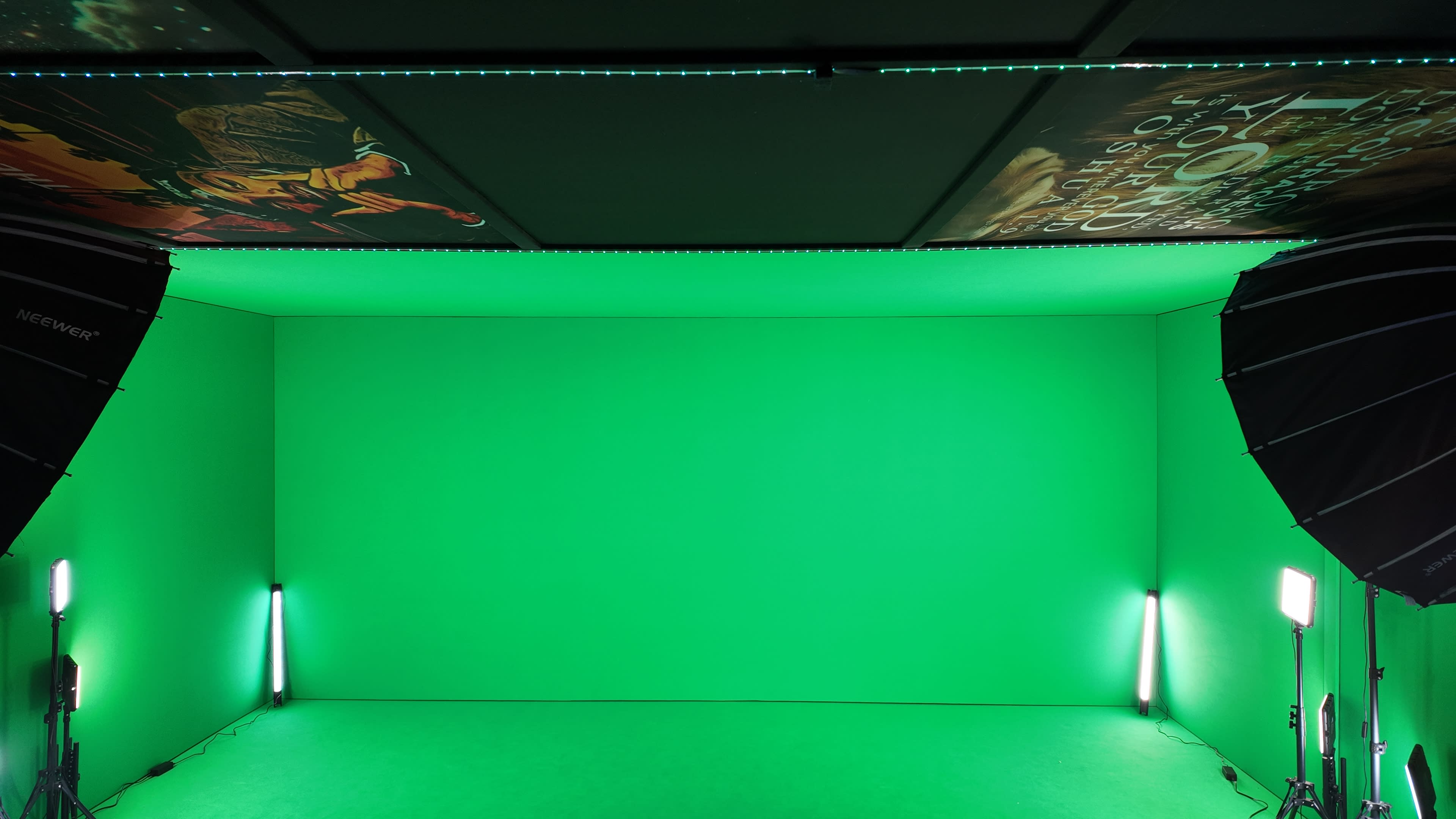 The image shows a green screen studio with two softbox lights on either side, and artwork visible on the ceiling.