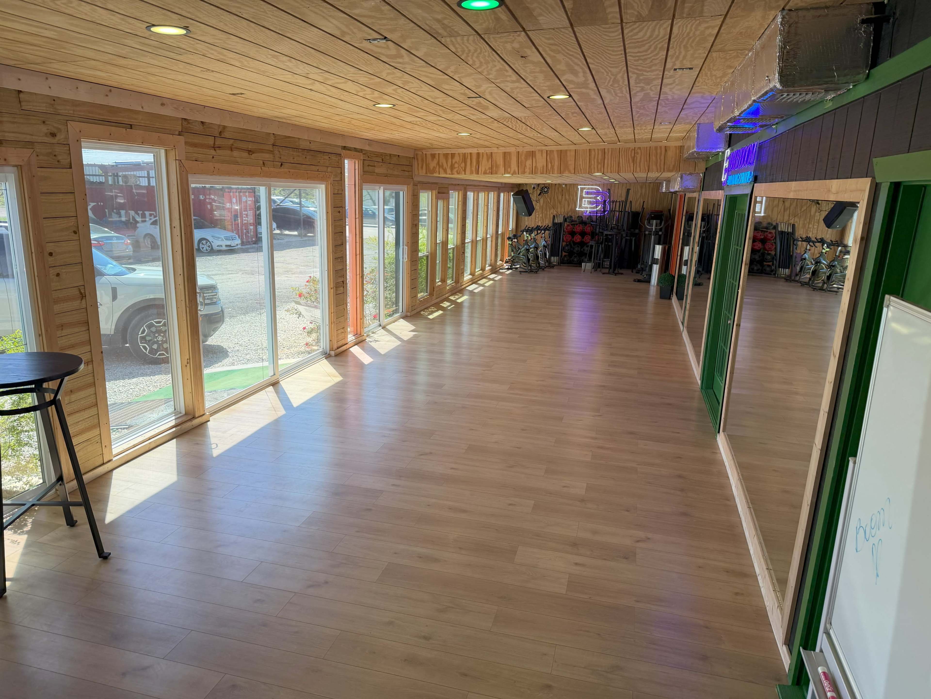 The image shows a spacious, well-lit interior with large windows along one side and wooden paneling on the walls and ceiling.