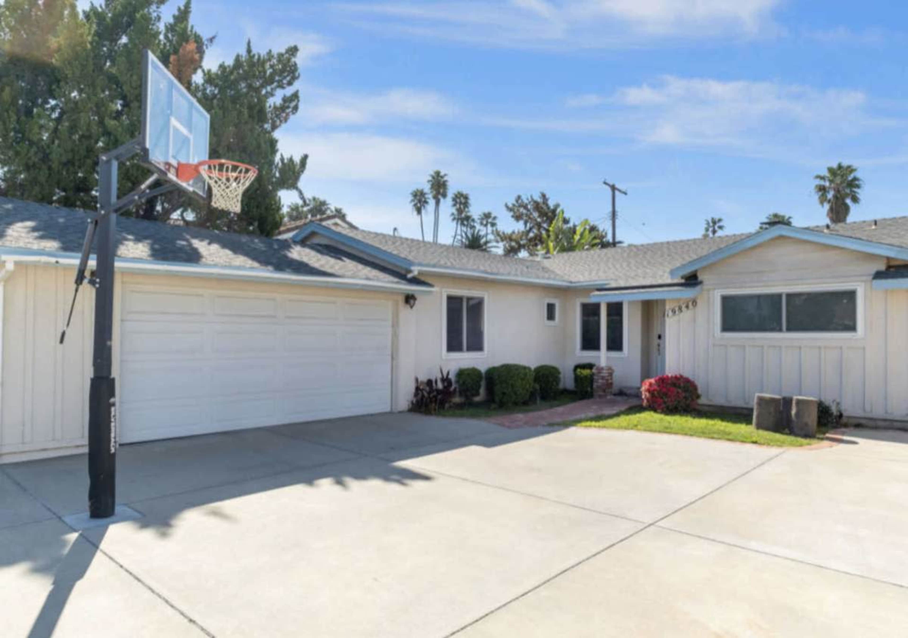 The image shows a suburban home with a basketball hoop in the driveway and a landscaped front yard.