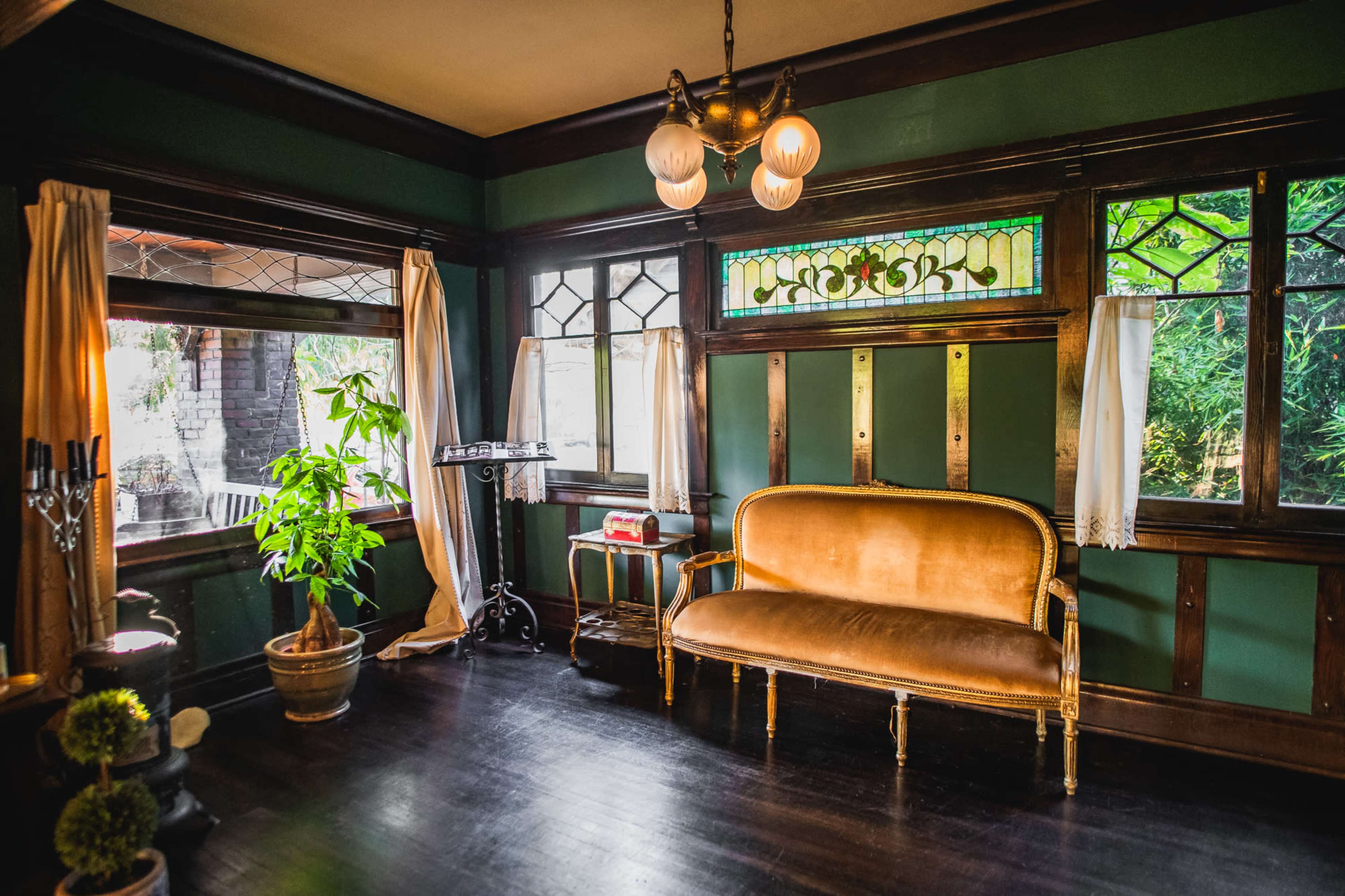 The image depicts a vintage room with green walls, a gold-colored sofa, and decorative stained glass windows.