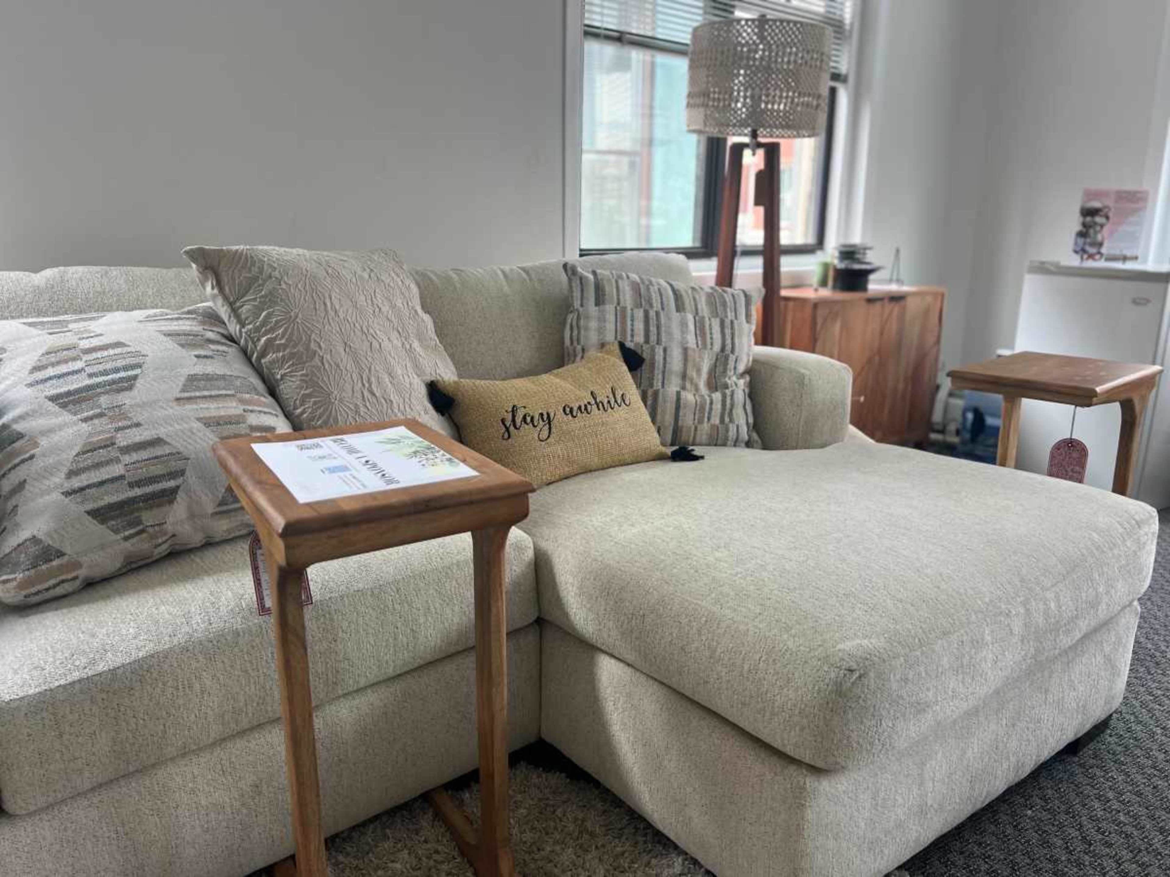A cozy living room featuring a light-colored sectional sofa with decorative pillows and two small side tables.