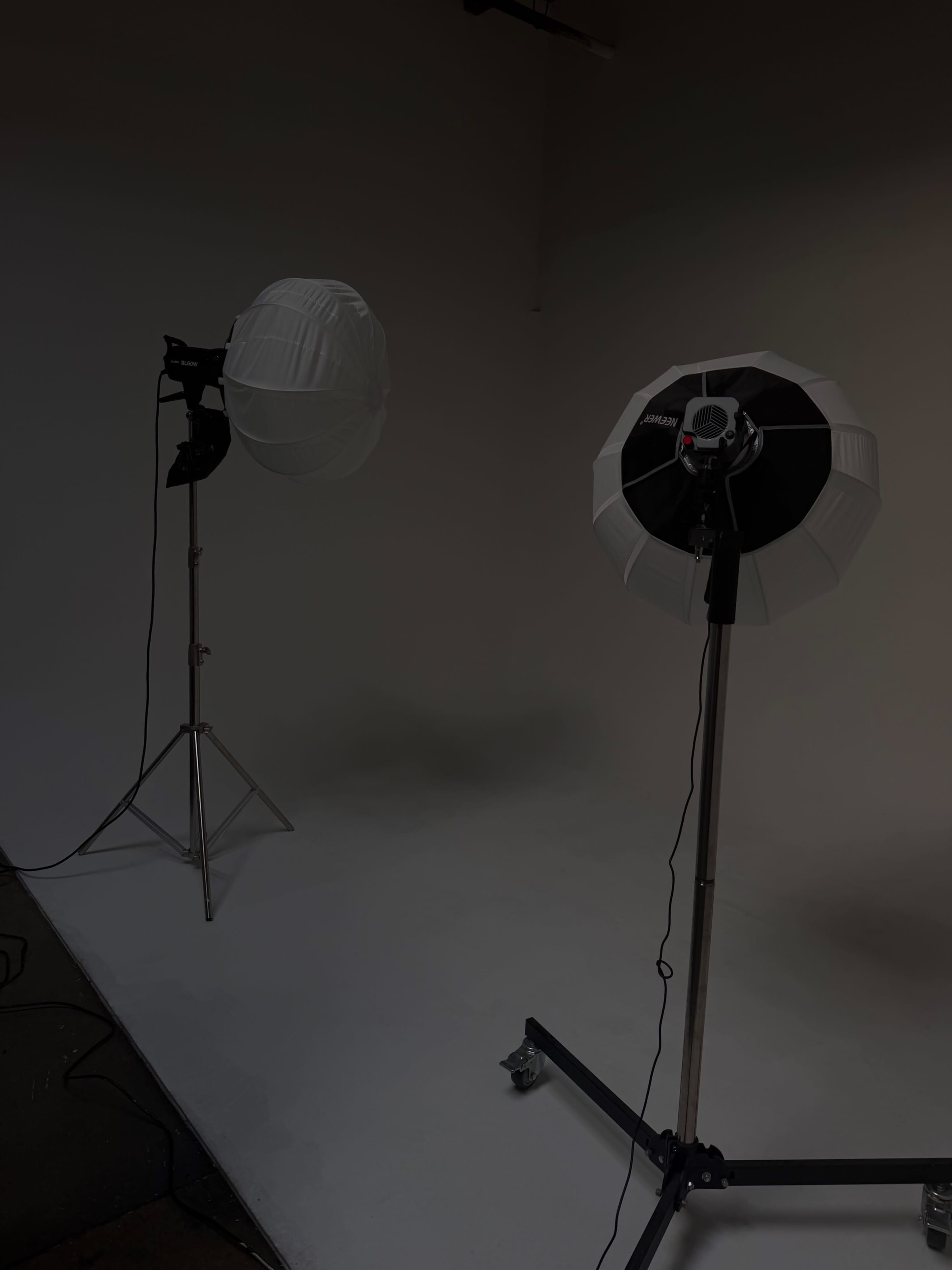 The image shows two lighting setups on stands in a studio with a plain backdrop.