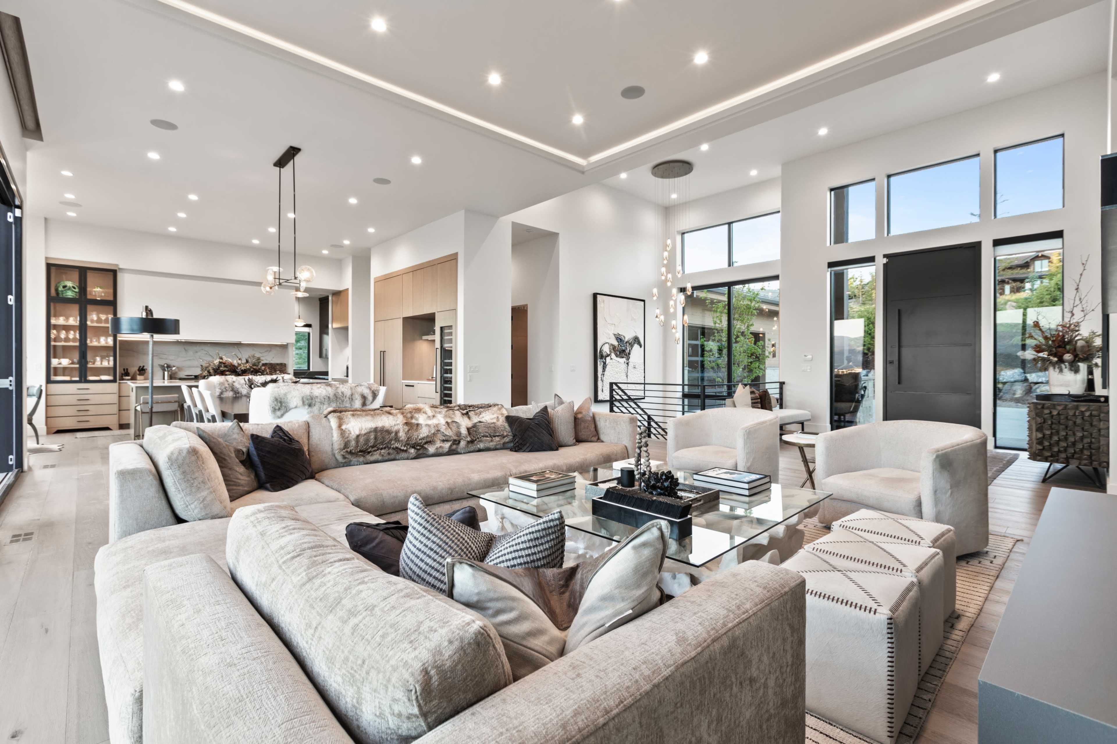 A modern, open-concept living area featuring a spacious sectional sofa, simple decorative elements, and large windows that provide natural light.