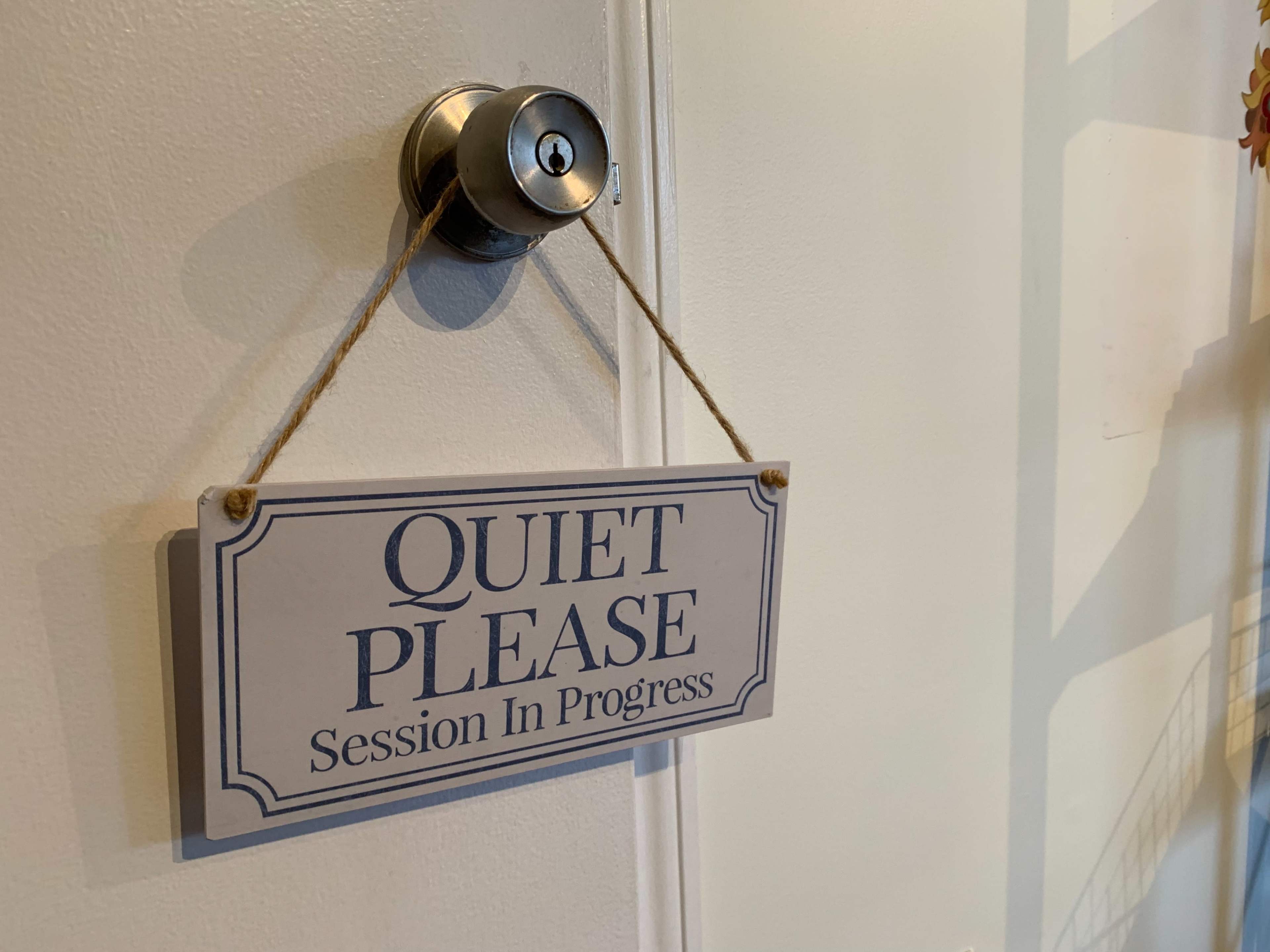 A sign hanging on a door reads "QUIET PLEASE Session In Progress."