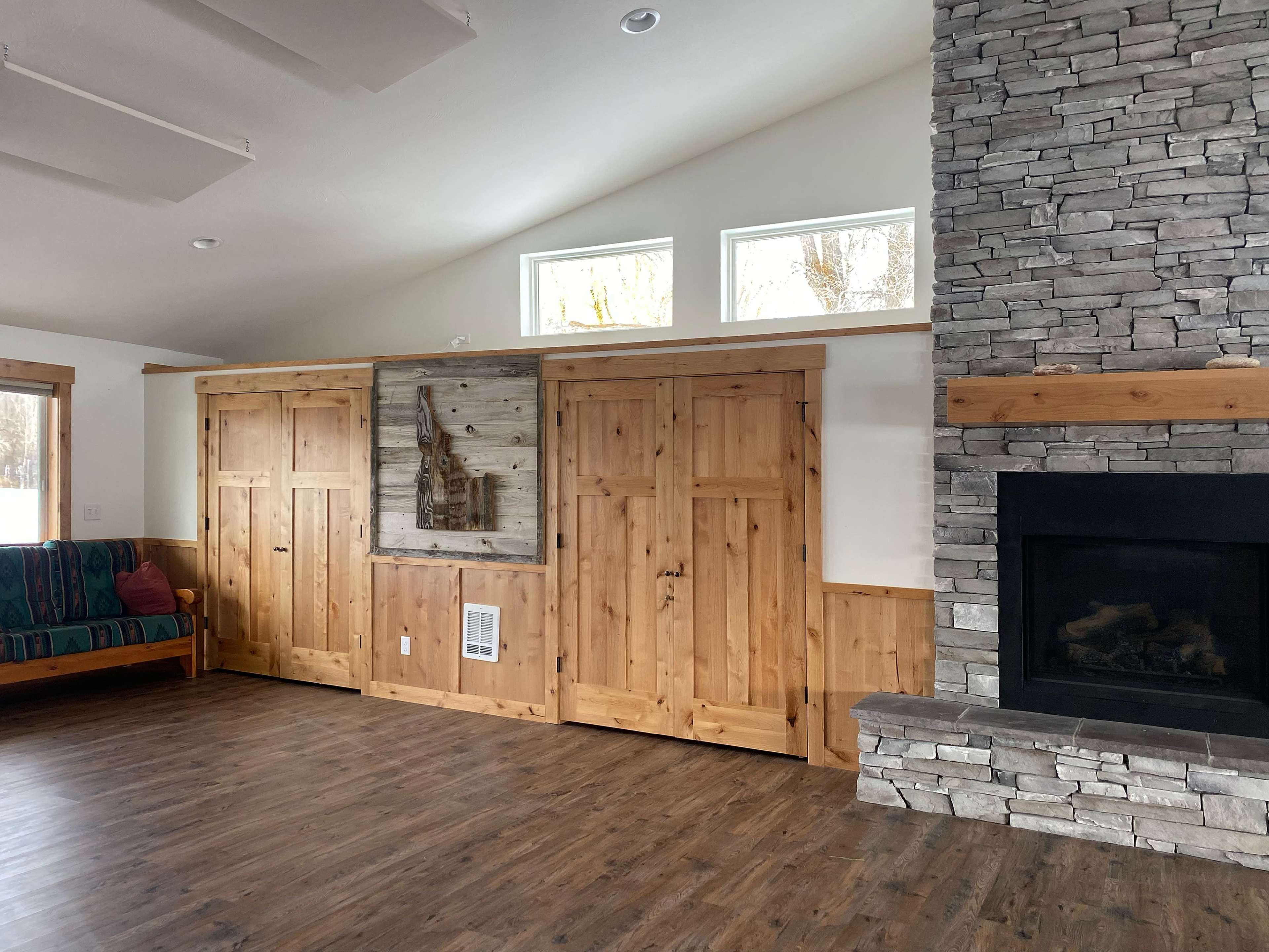 A modern interior space with wooden cabinets and a stone fireplace, set against a backdrop of large windows.