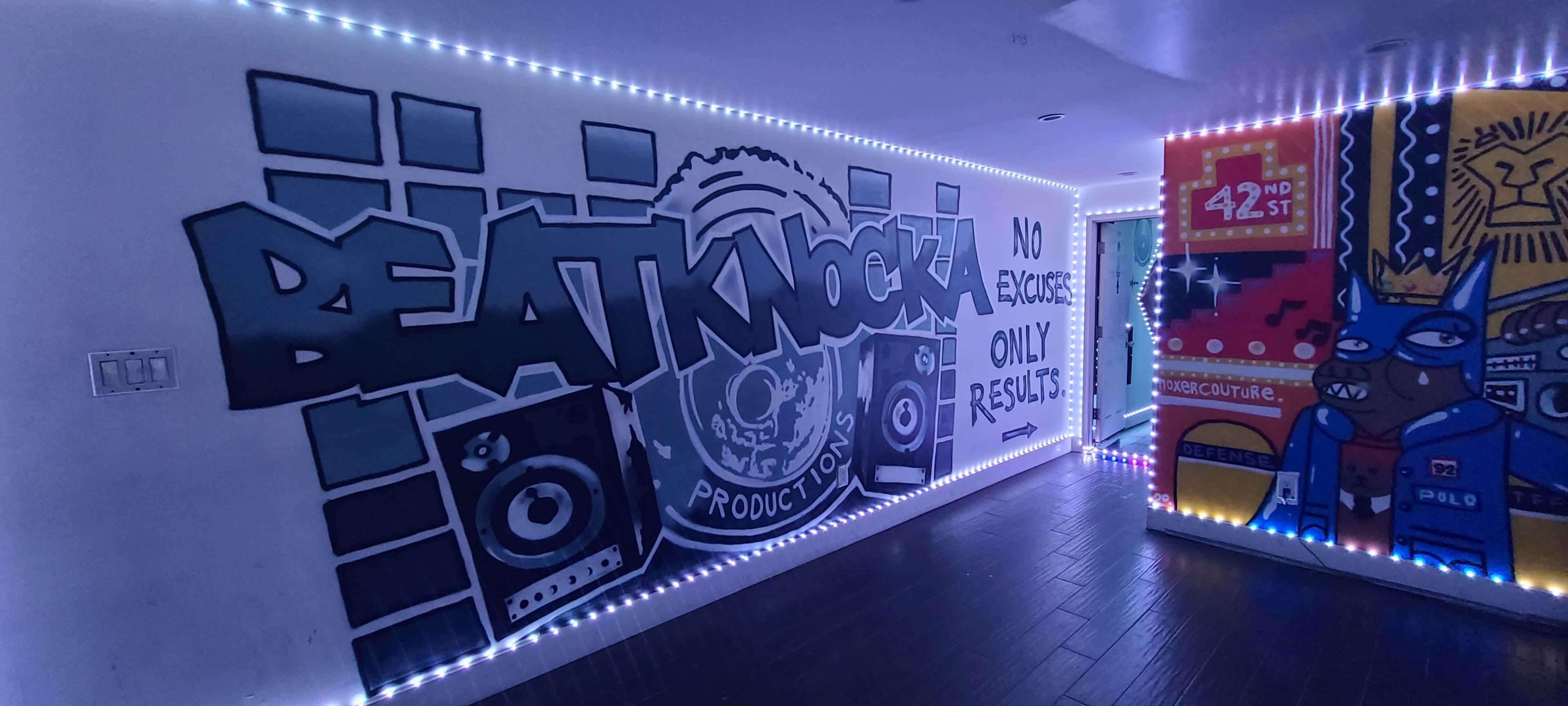 A hallway featuring vibrant graffiti art with the text "BEAT KNOCKS PRODUCTIONS" and accentuated by LED lights along the walls.