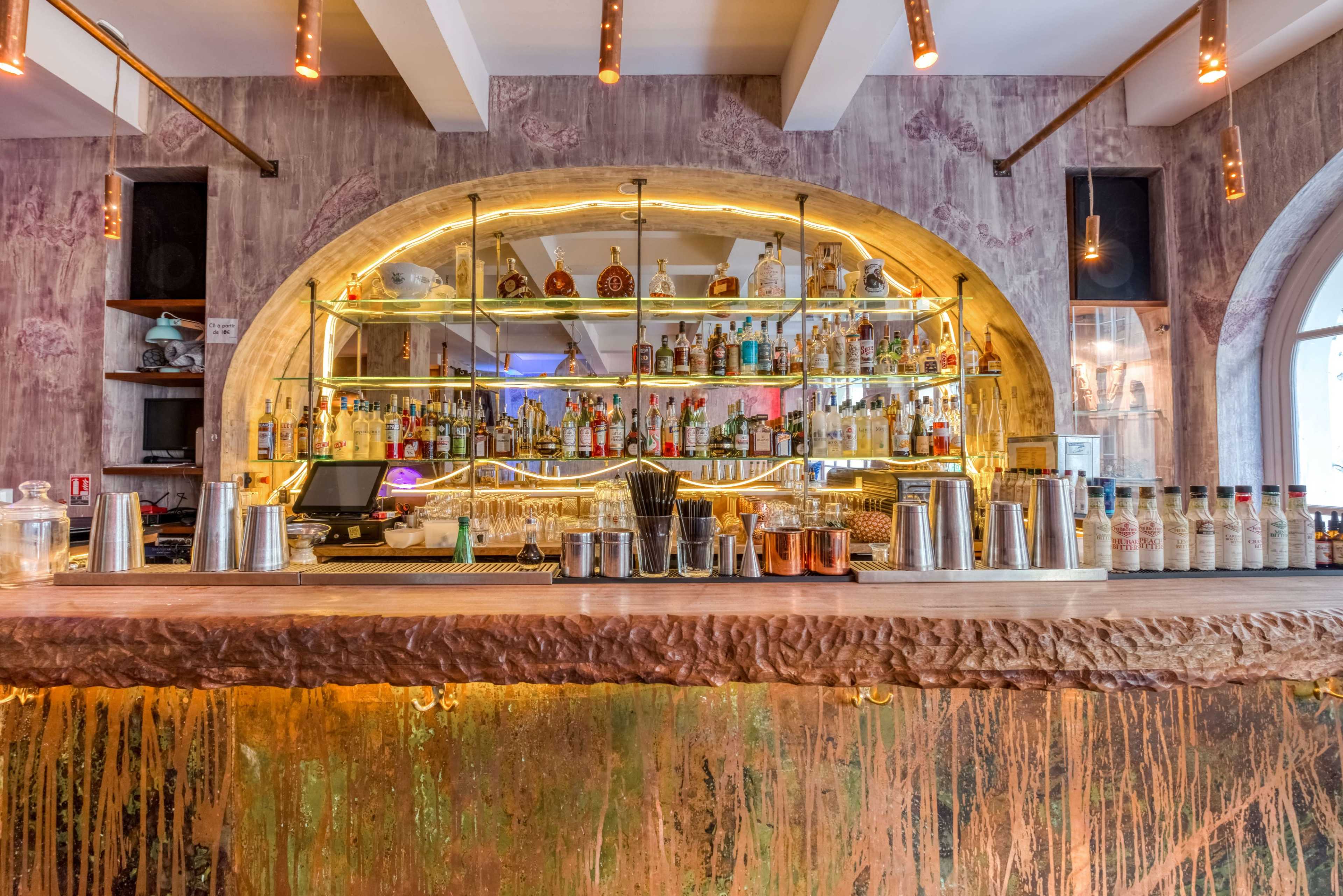 A well-stocked bar features an illuminated display of various bottles behind a polished countertop.