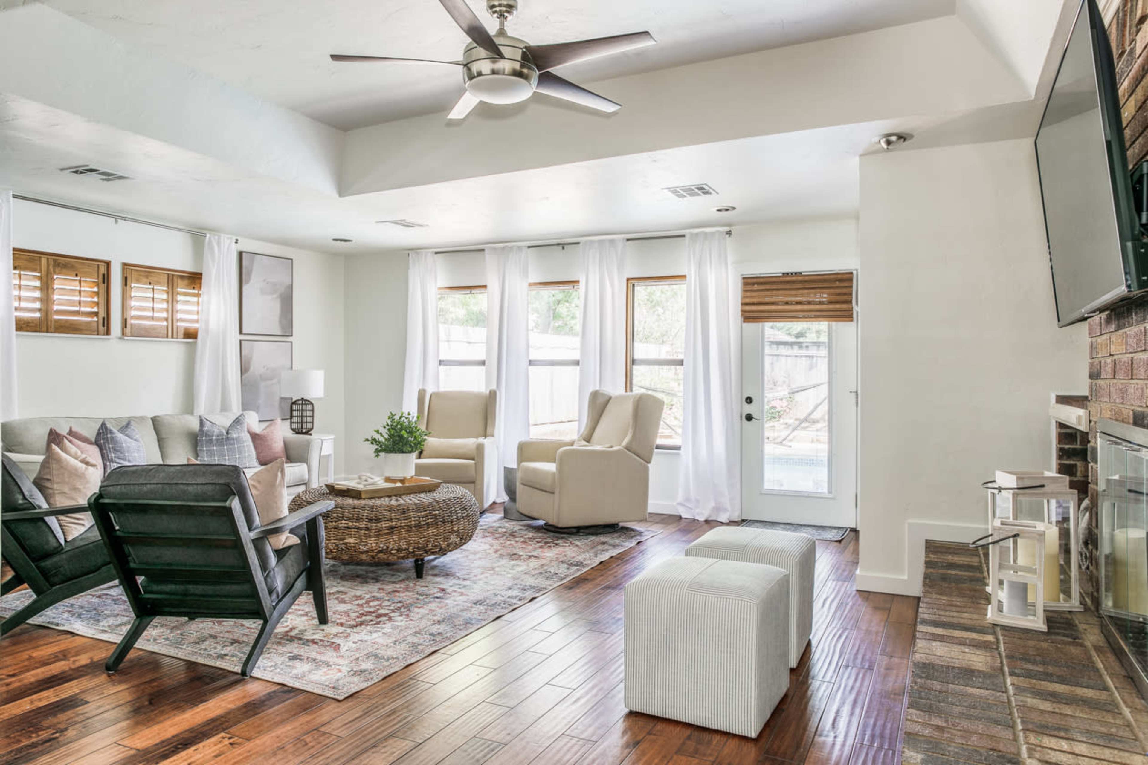 A modern living room with a comfortable seating area, large windows, and a door leading to an outdoor space.