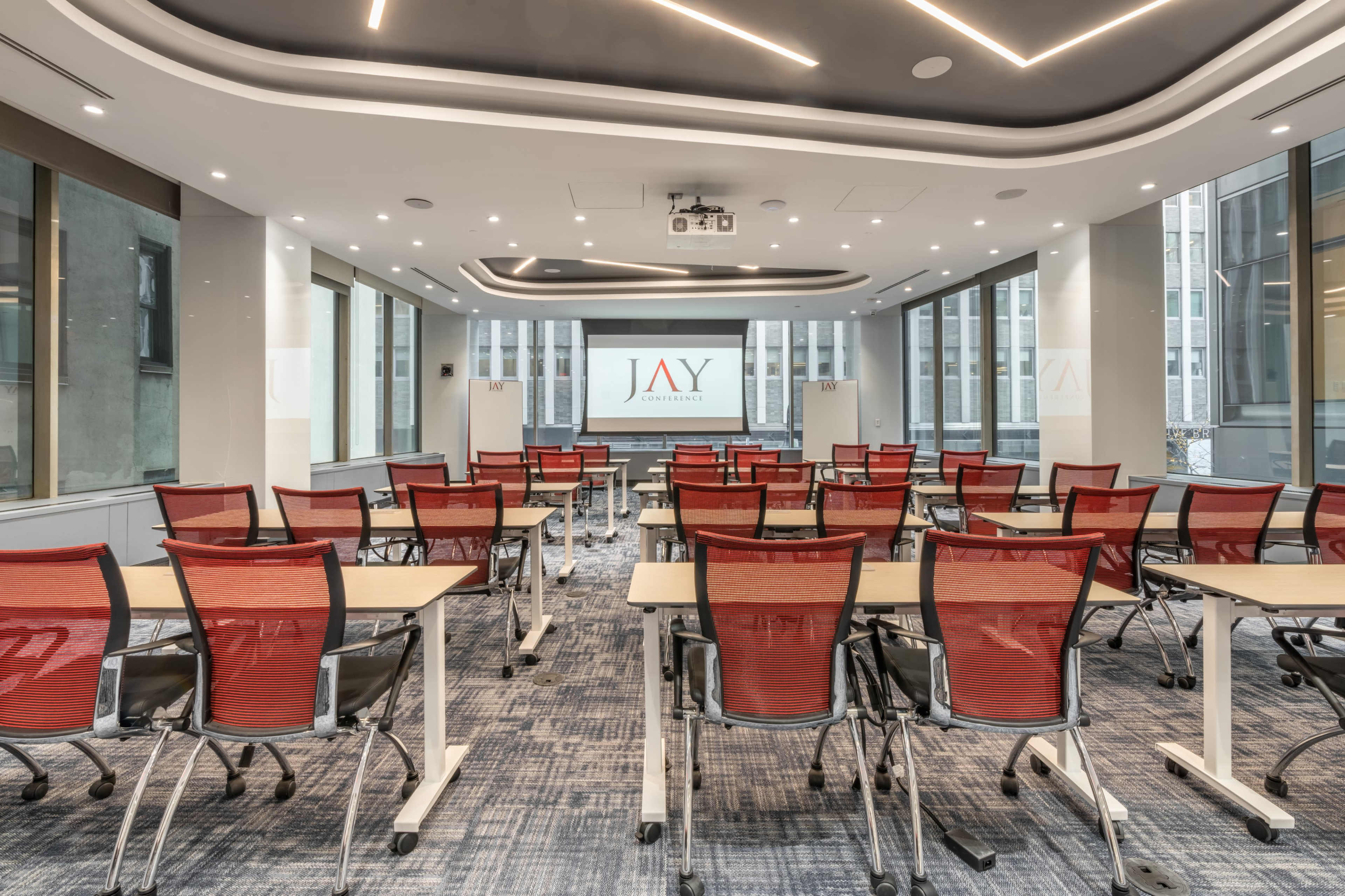 A modern conference room with rows of red chairs facing a presentation screen.