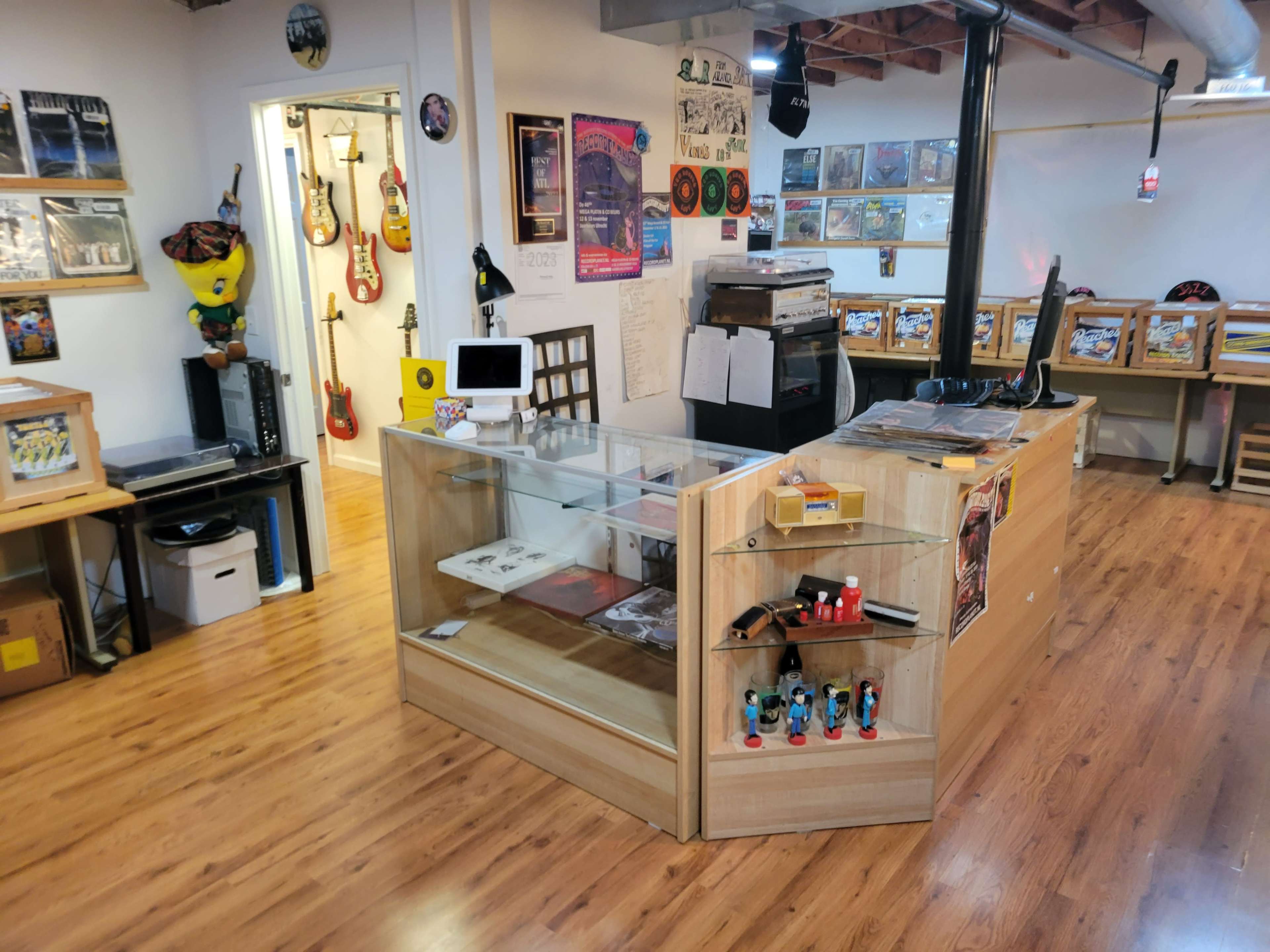 A music-themed store interior with display cases, instruments on the walls, and a counter for transactions.