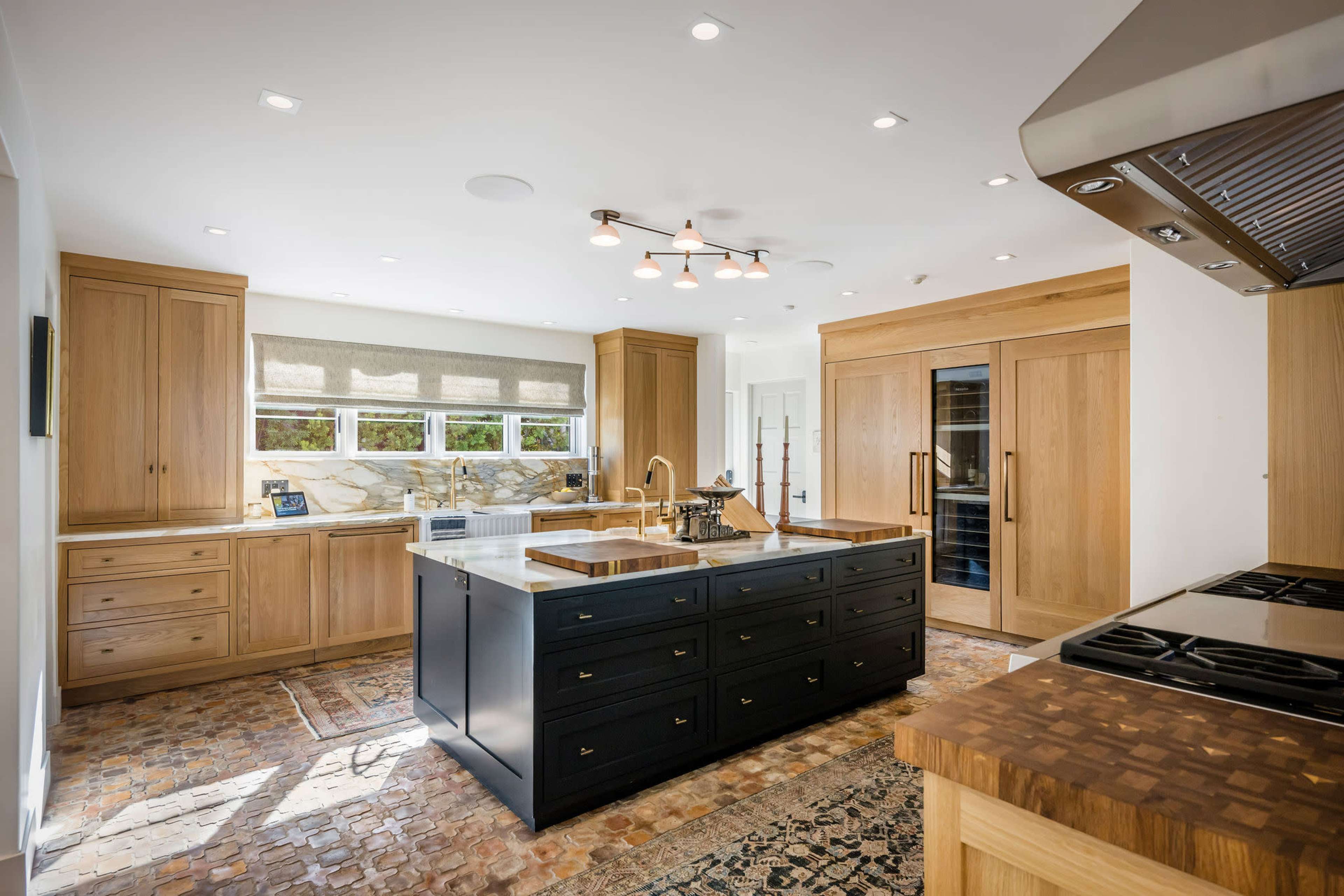 The kitchen features a central island with a dark countertop, wooden cabinetry, and a combination of modern appliances.