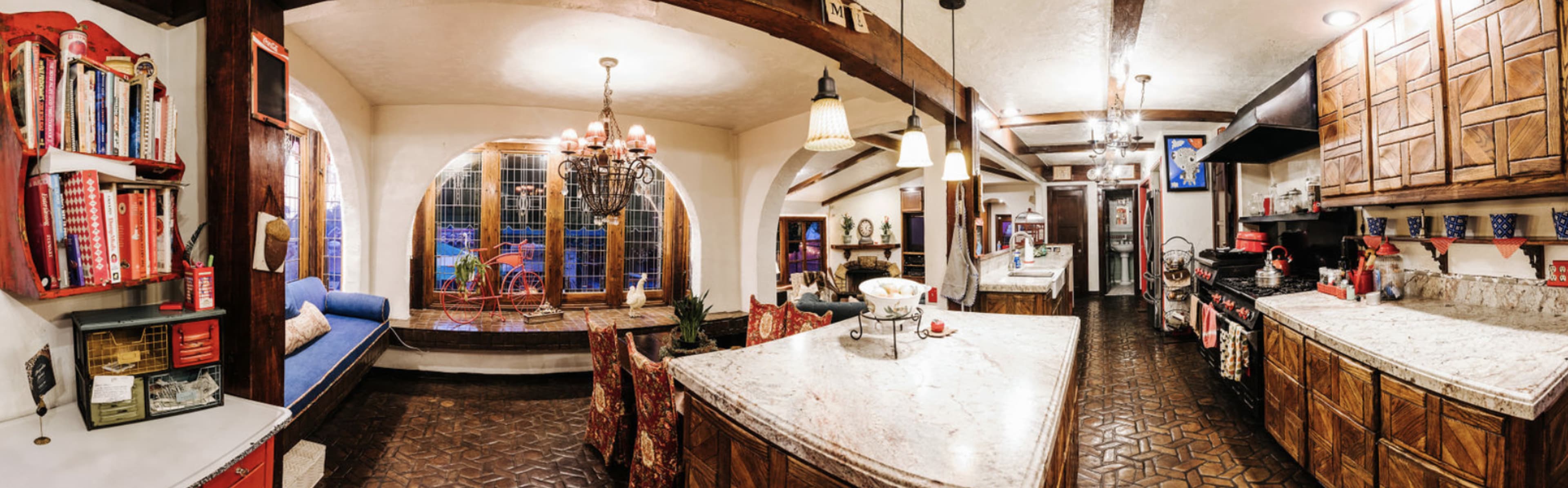A spacious kitchen features a large island with a marble countertop, wooden cabinets, and an adjacent dining area with a window reading nook.