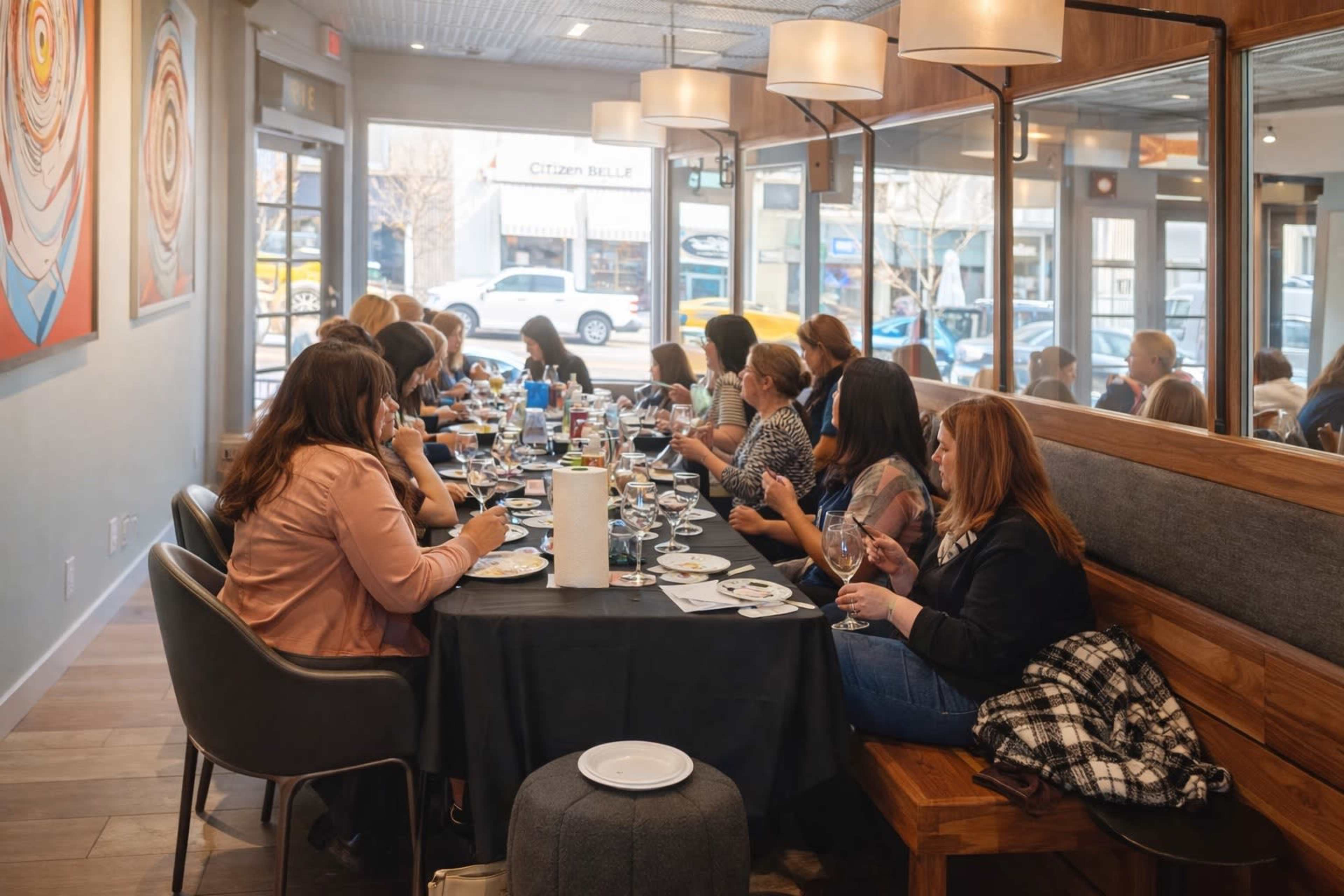 A long table filled with people dining and socializing in a restaurant.