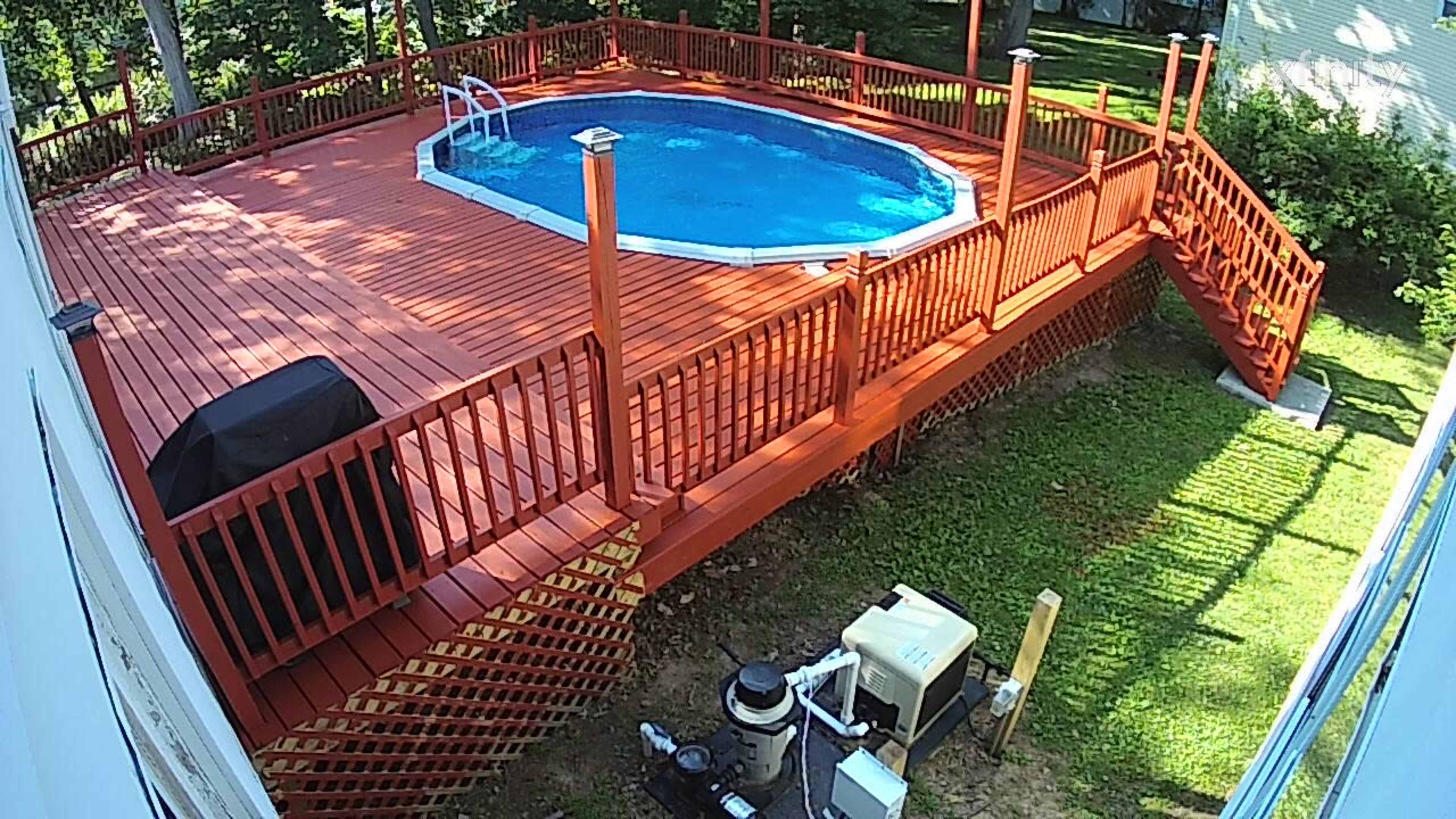 The image shows a backyard scene with a circular pool surrounded by a wooden deck, chairs, and a pool pump unit nearby.