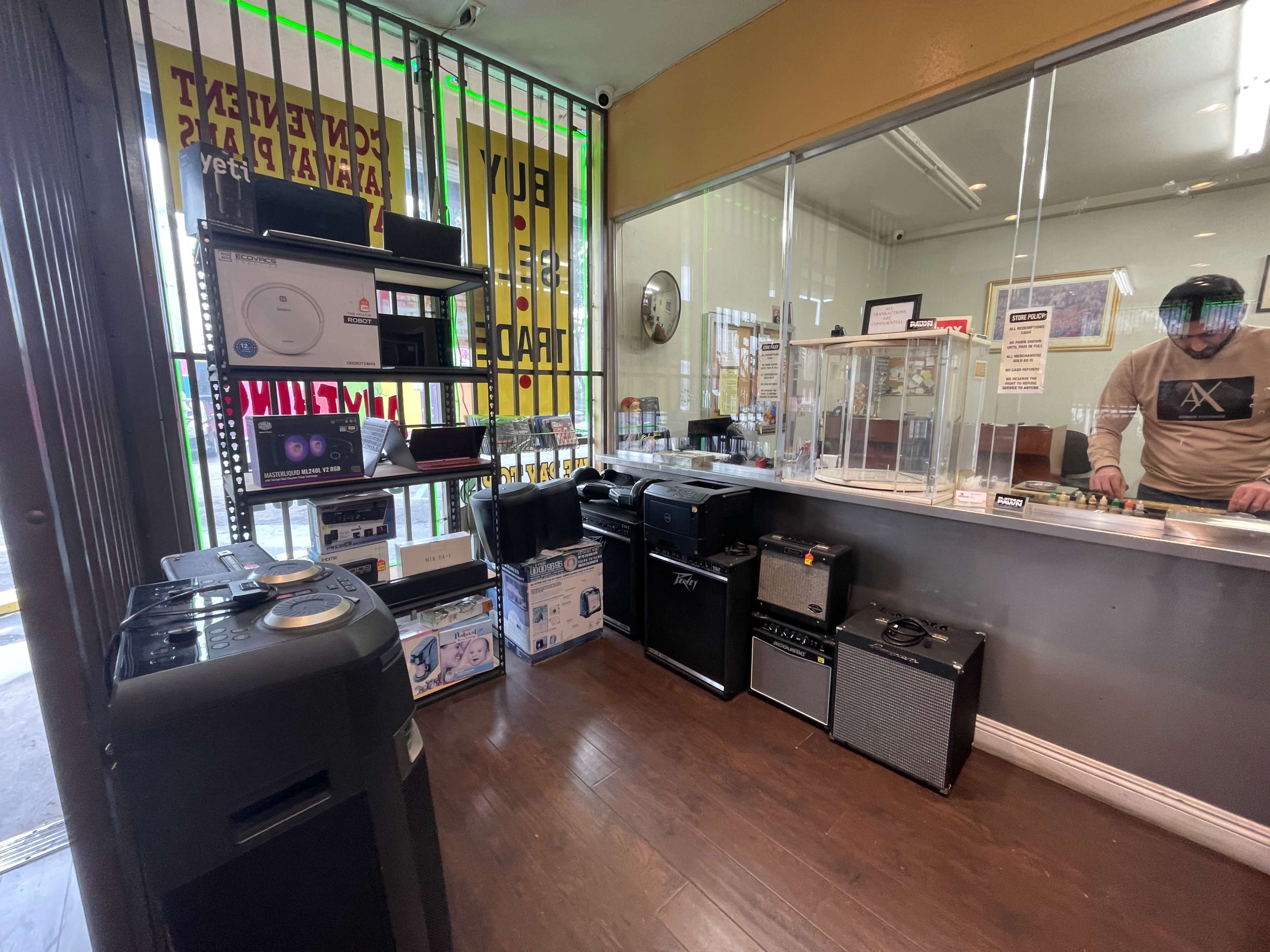 A store interior displays various audio equipment, including amplifiers, speakers, and turntables, along with a service counter behind a glass display.