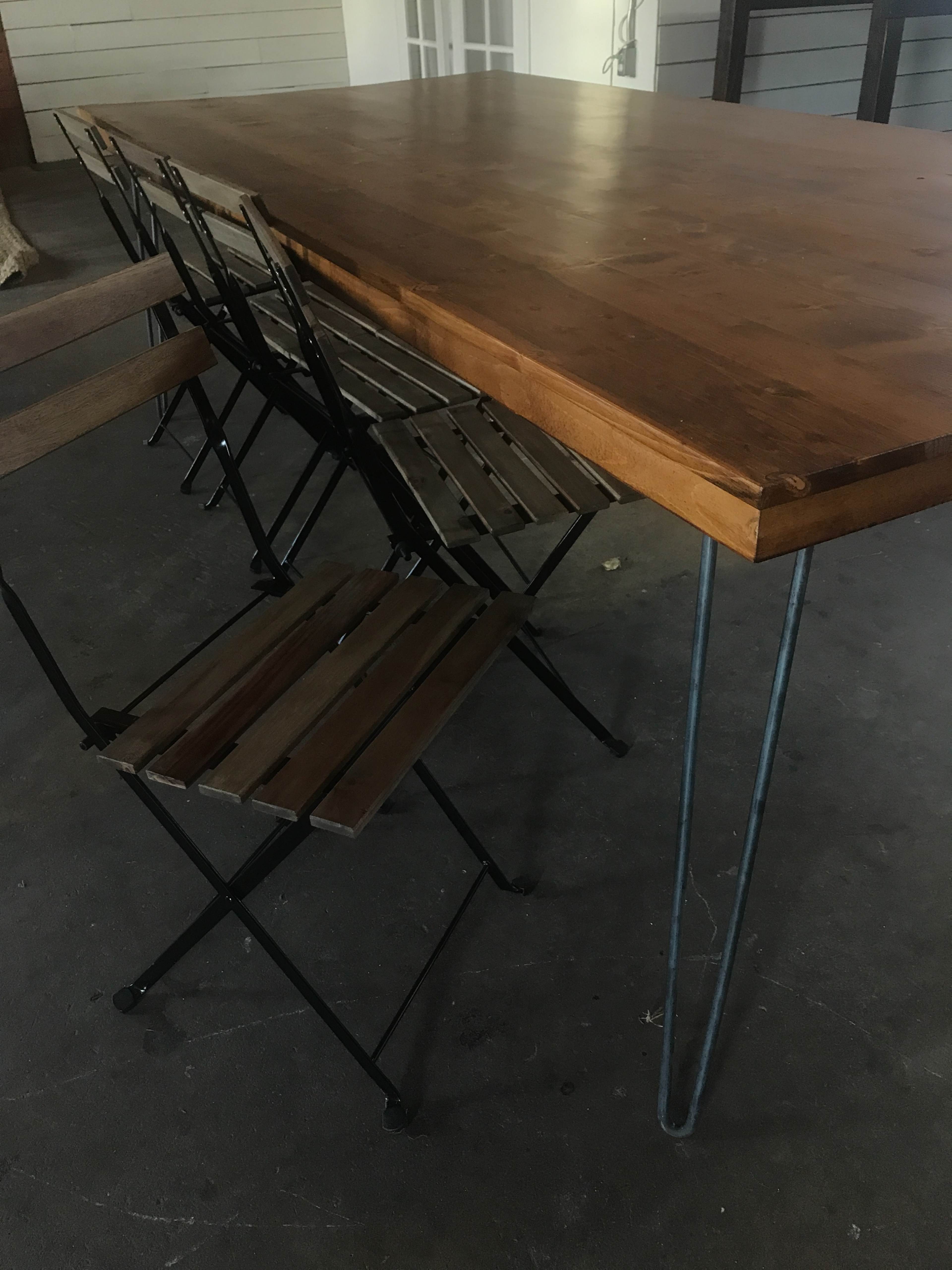 A wooden dining table with metal legs is positioned alongside several folding metal chairs.