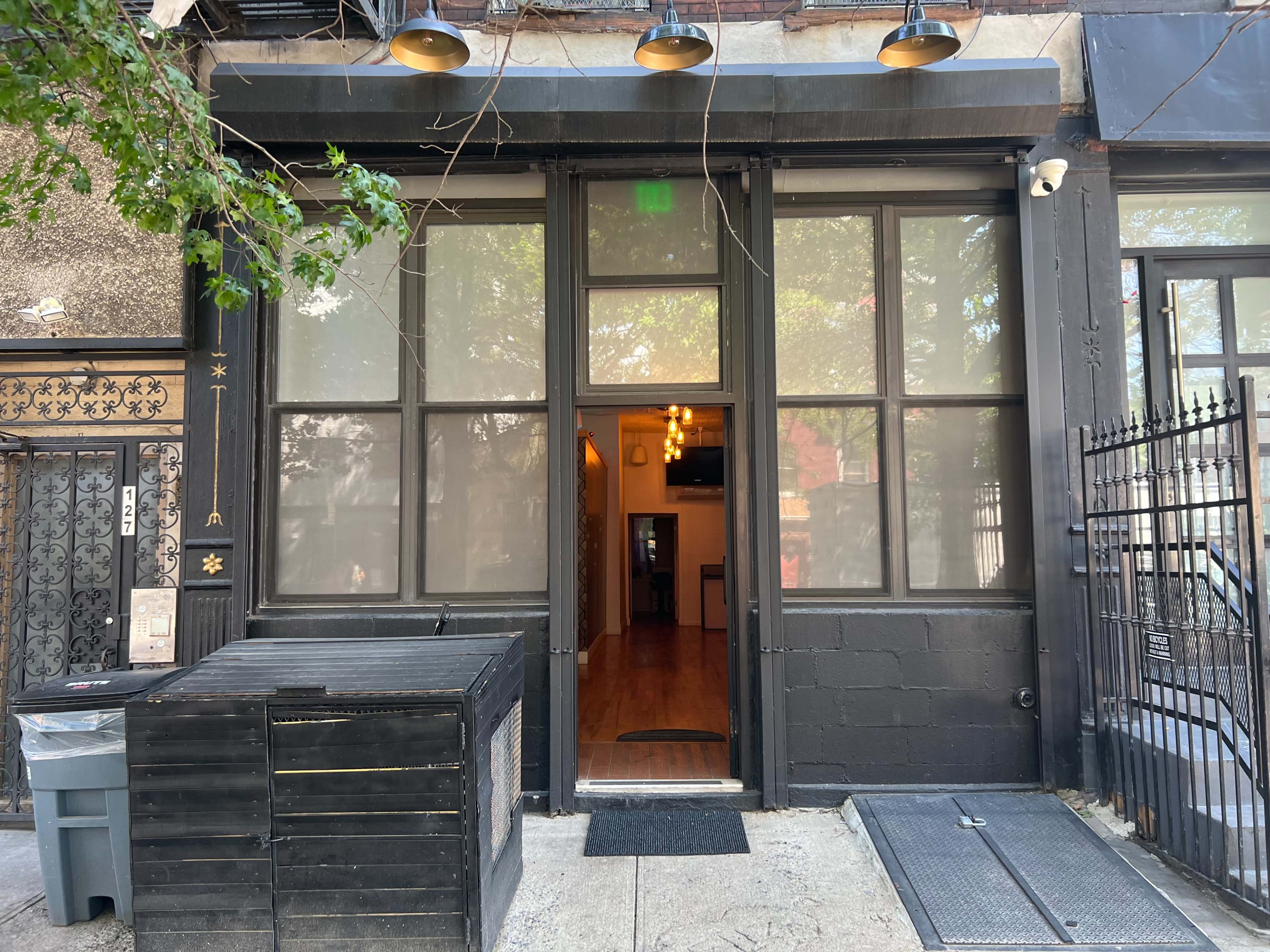 The entrance of a building with large windows, a door in the center, and outdoor lighting fixtures above the door.