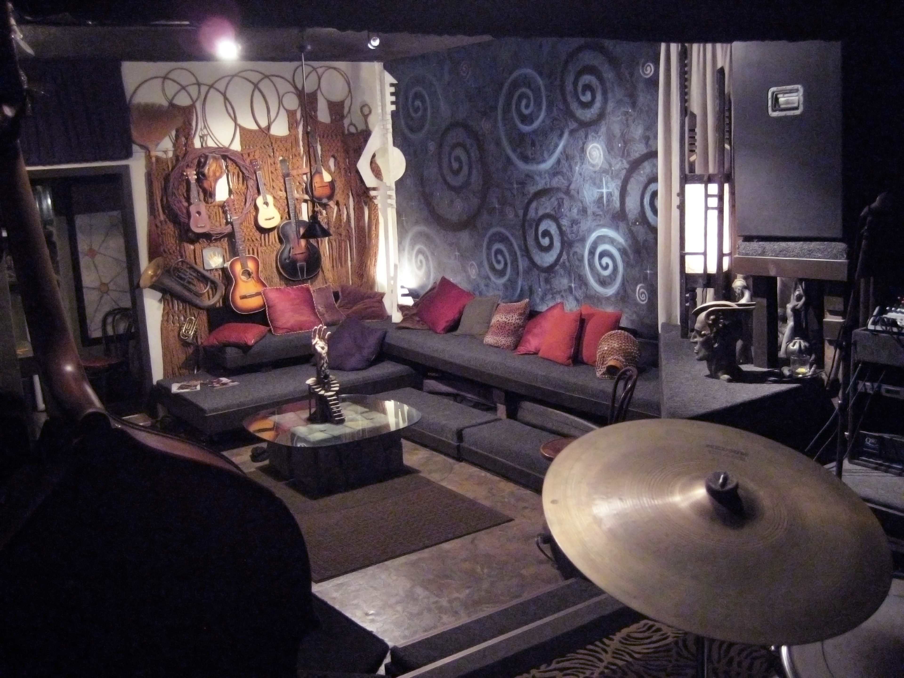 A music-themed lounge with a dark sofa, decorative guitars on the wall, and a small glass table in the center.