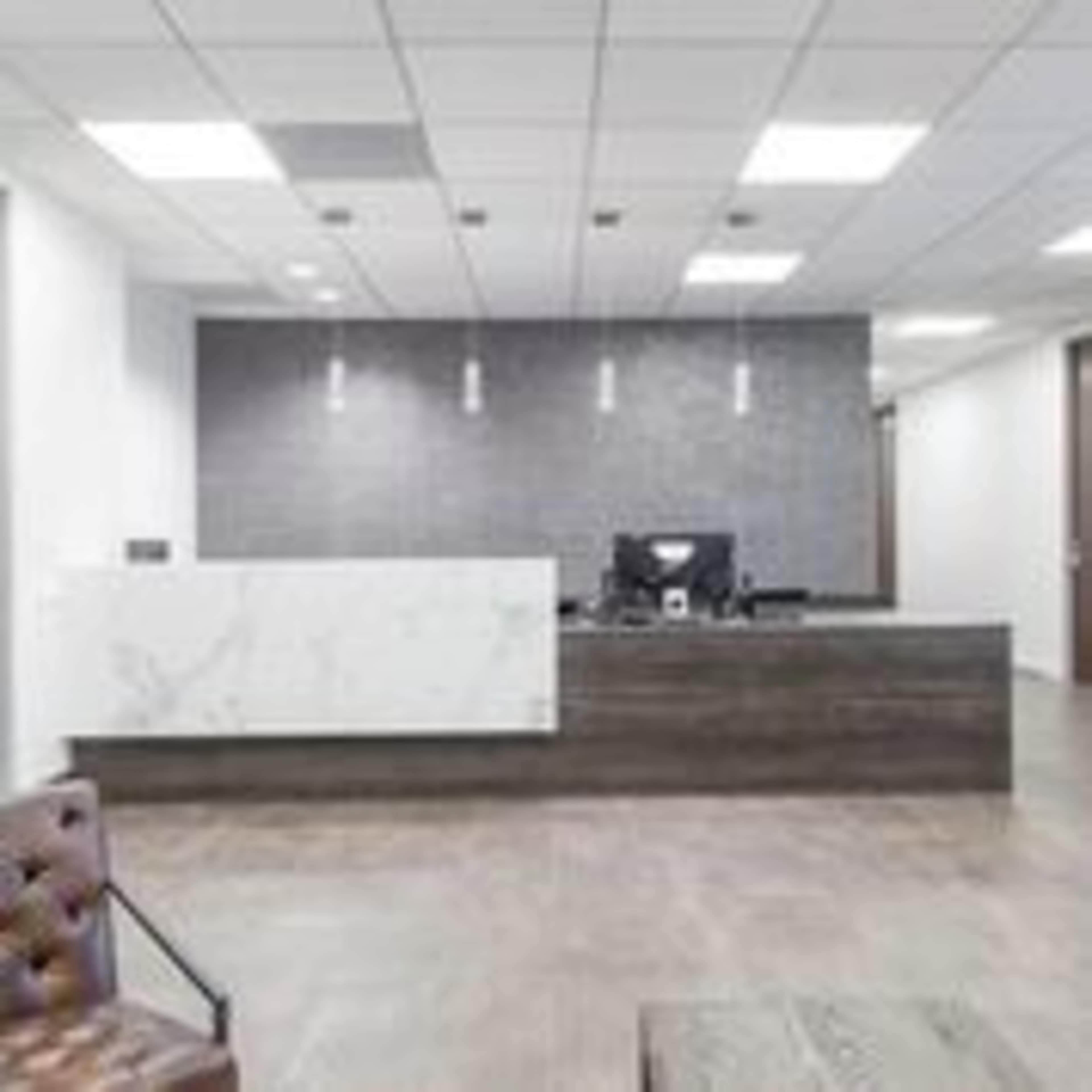 A modern reception area featuring a desk with a marble front, a computer monitor, and a minimalist design.