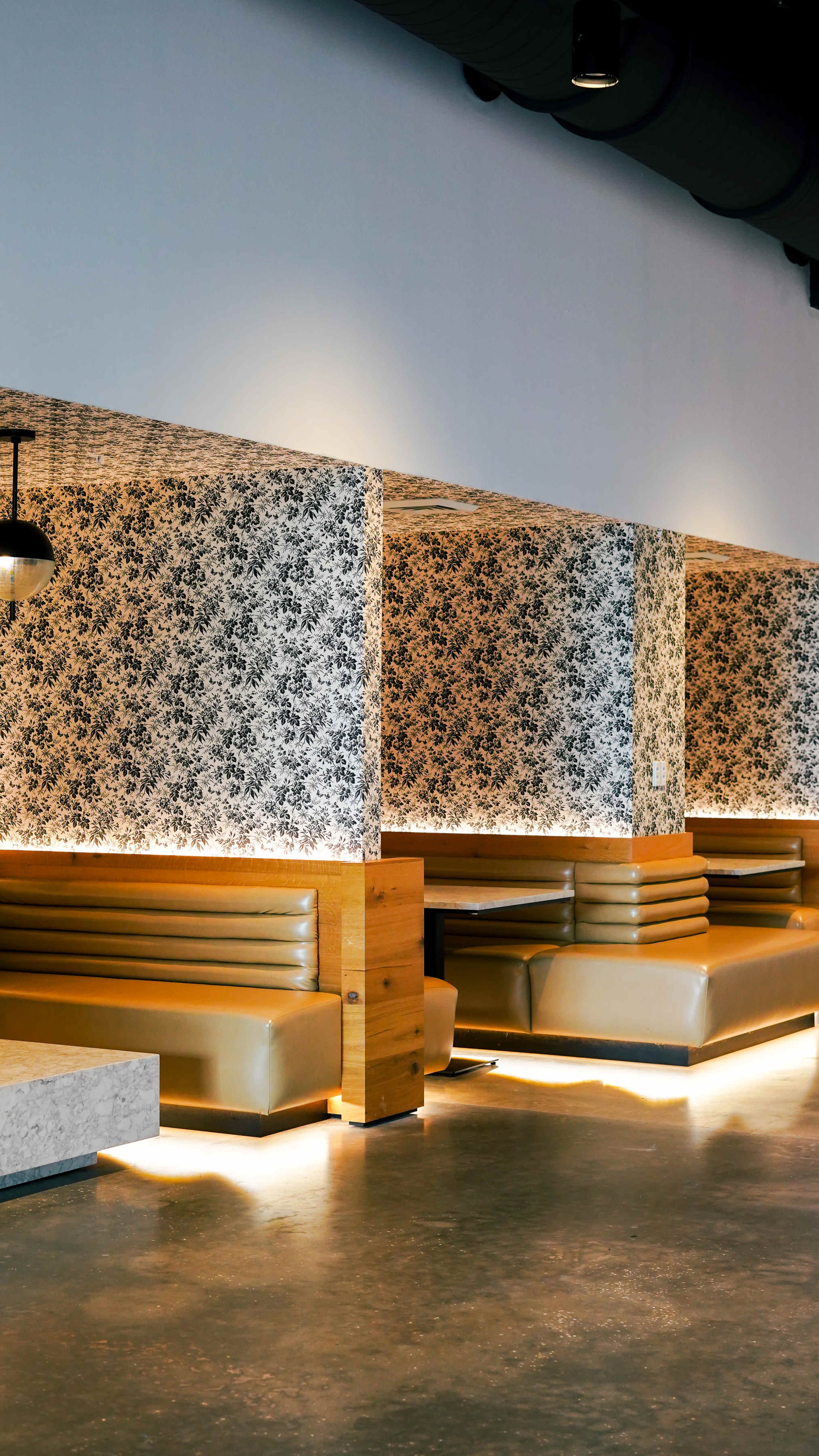 The image showcases a modern restaurant interior featuring wooden booths and decorative wallpaper.