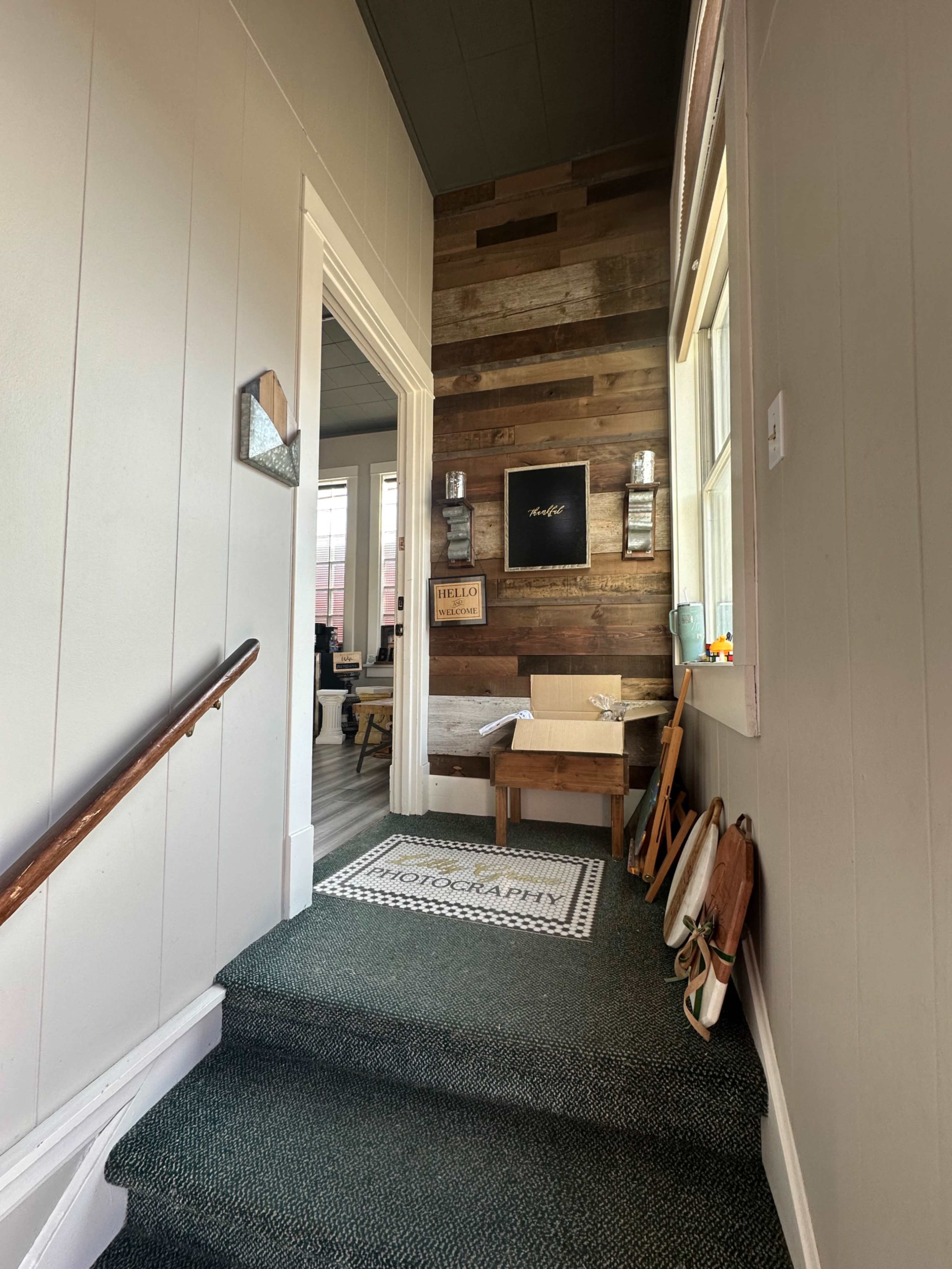 A stairway leads to a brightly lit hallway adorned with wood paneling and a decorative rug.