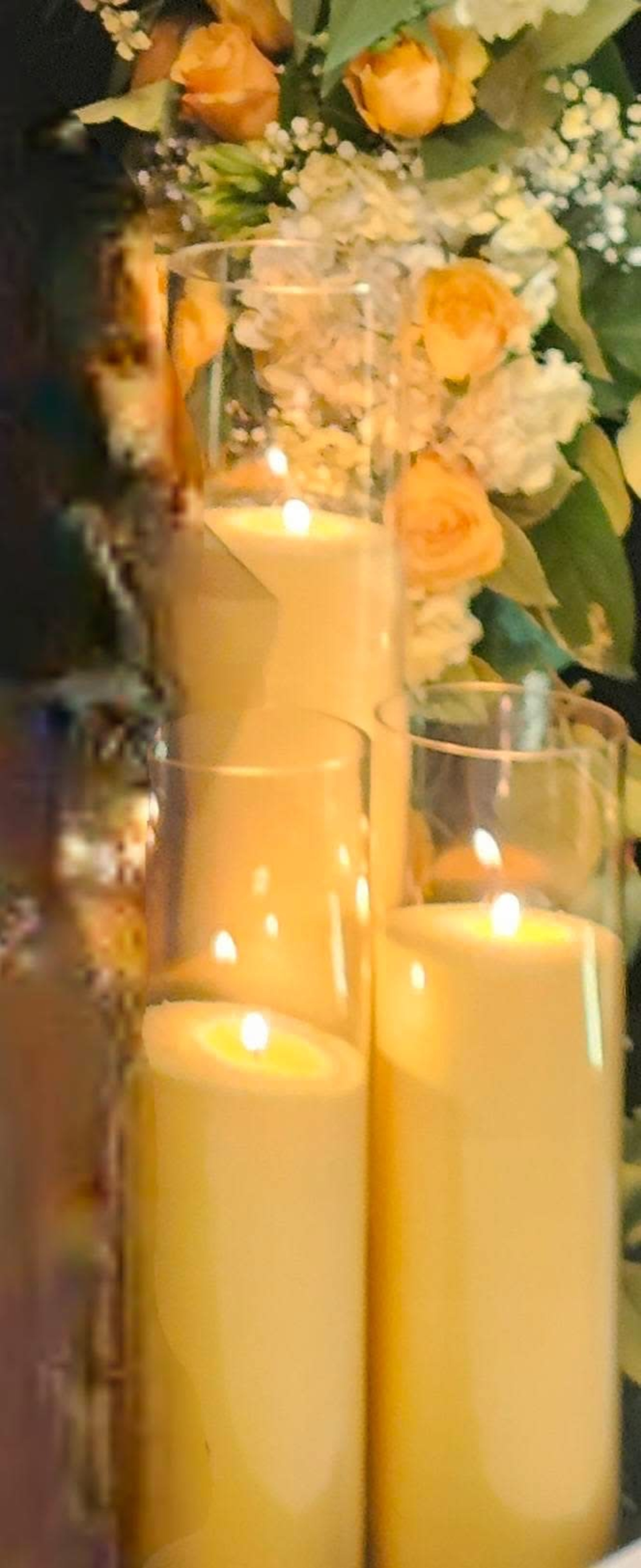 The image features several lit candles arranged among decorative flowers and greenery.