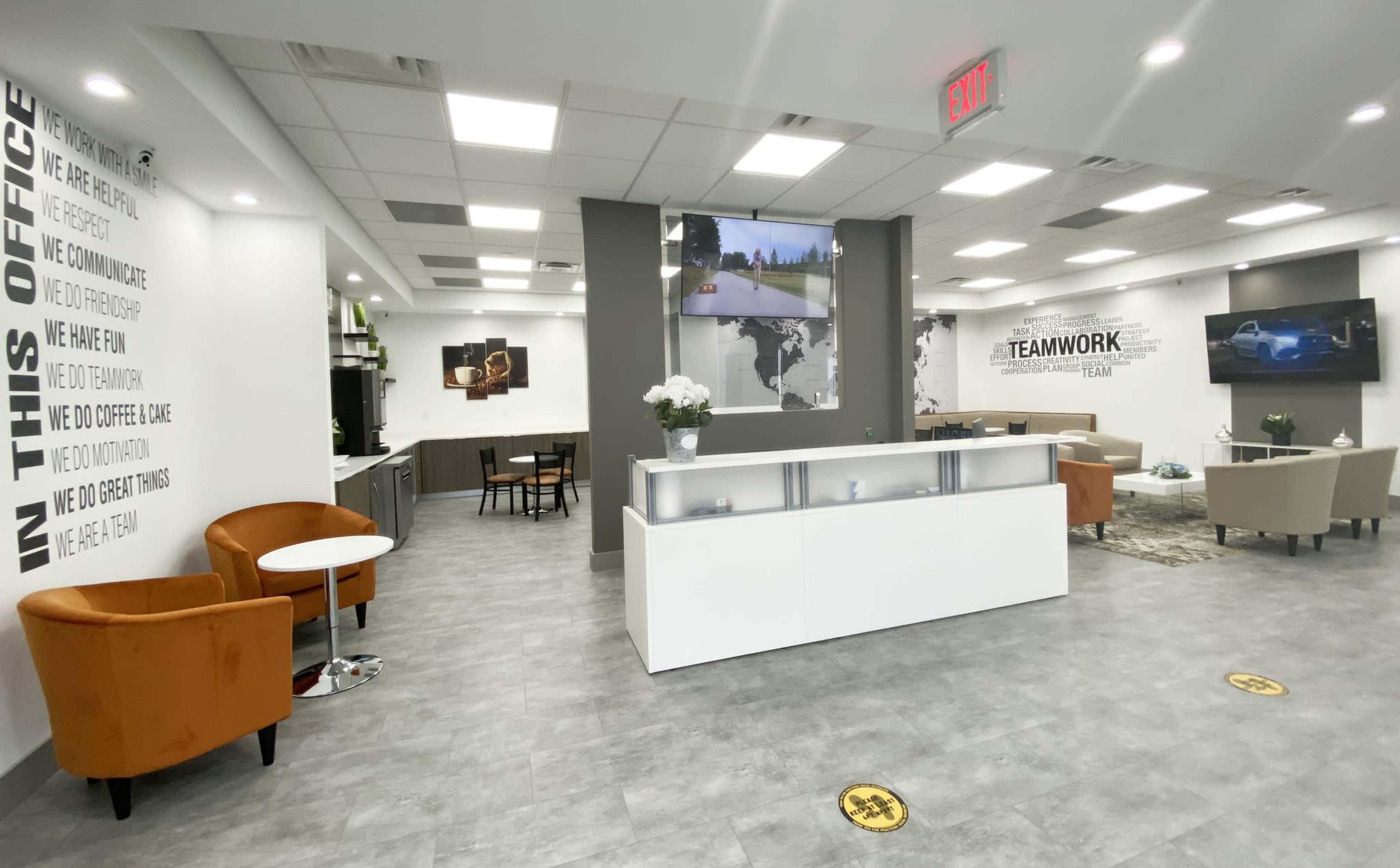 A modern office reception area with a clean layout, featuring a front desk, seating arrangements, and motivational phrases on the walls.