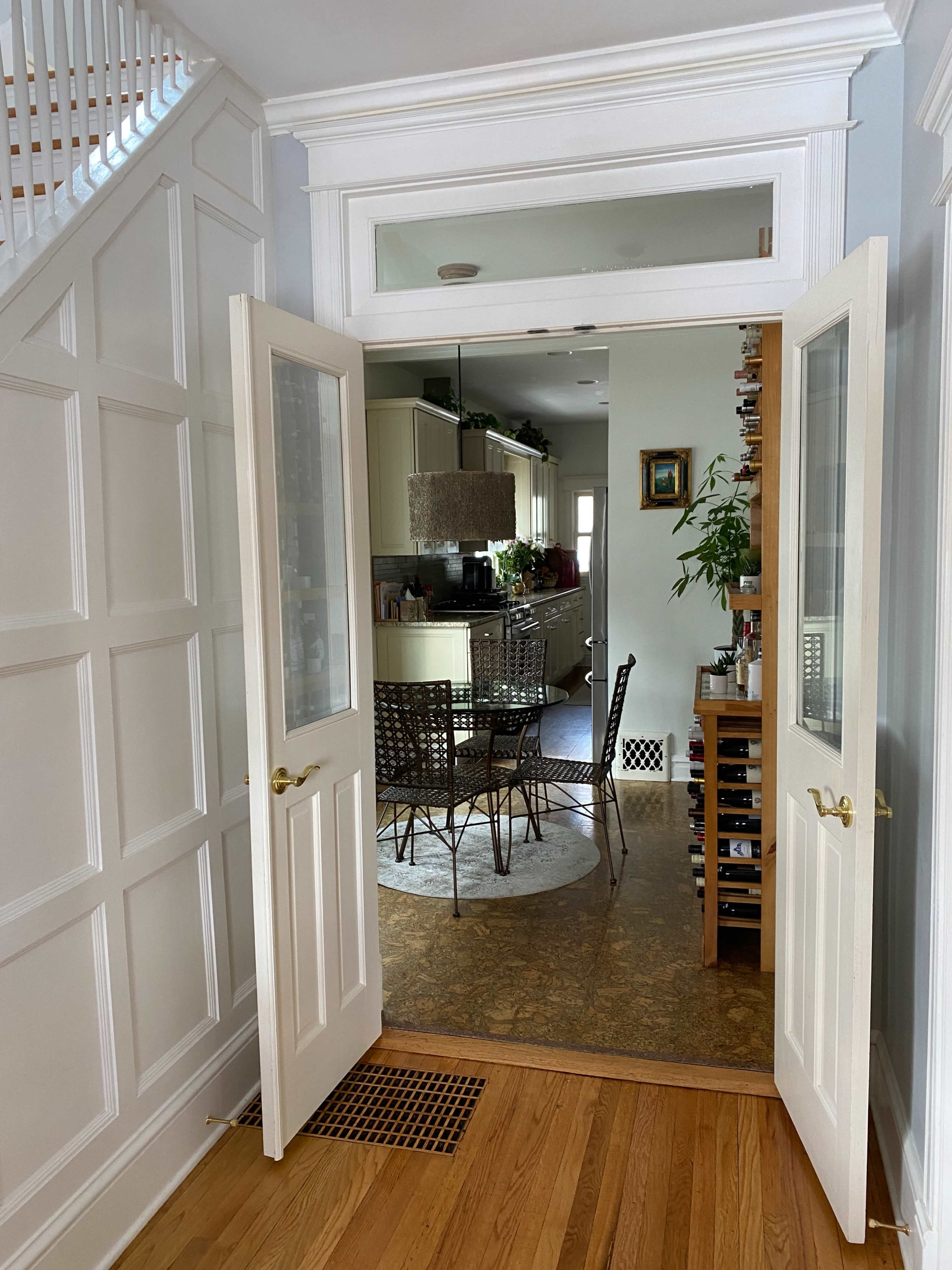 An open double door leading from a foyer into a dining area with a round table and chairs.