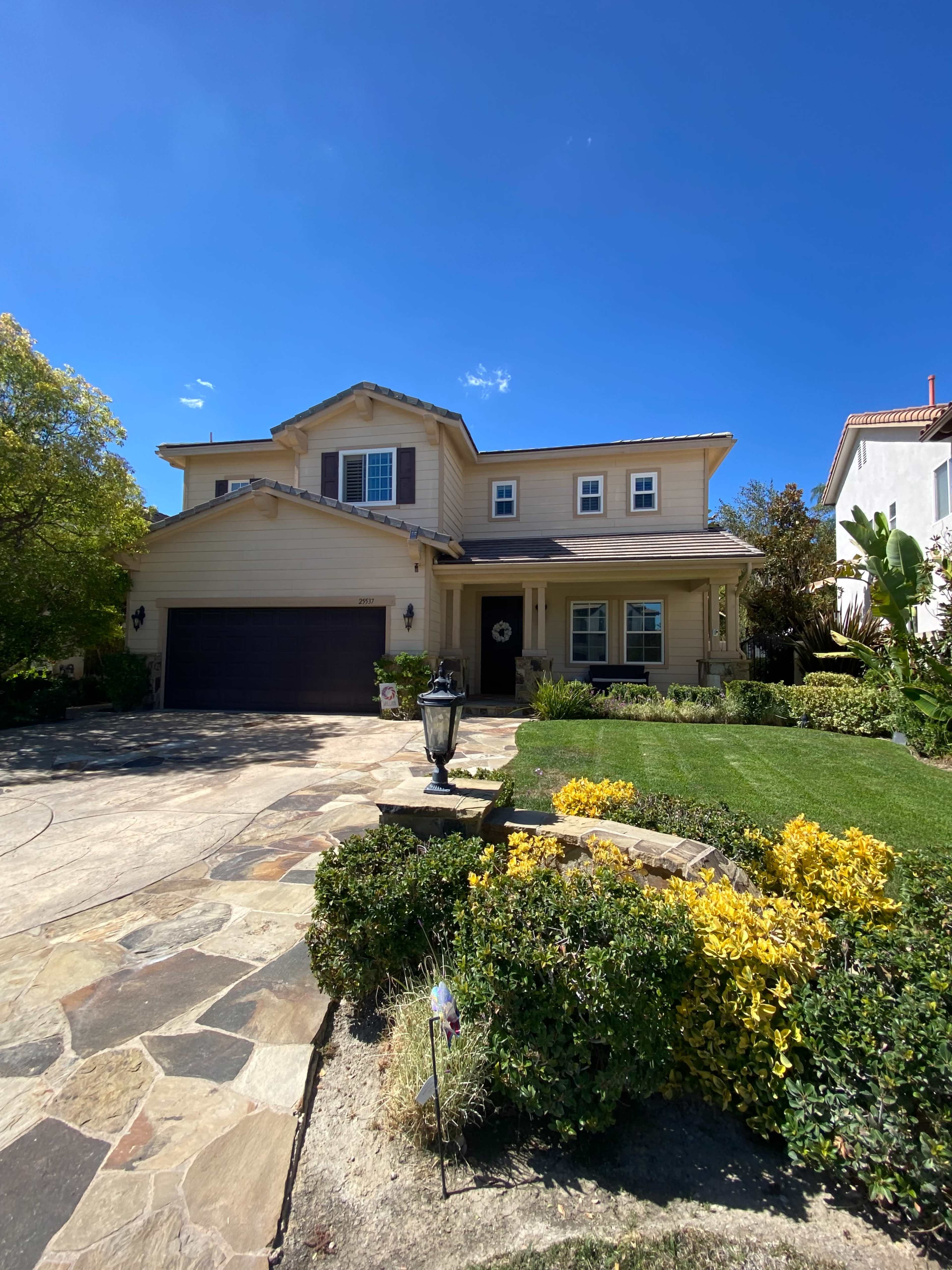 A two-story house with a large front yard, a stone pathway, and a garage.