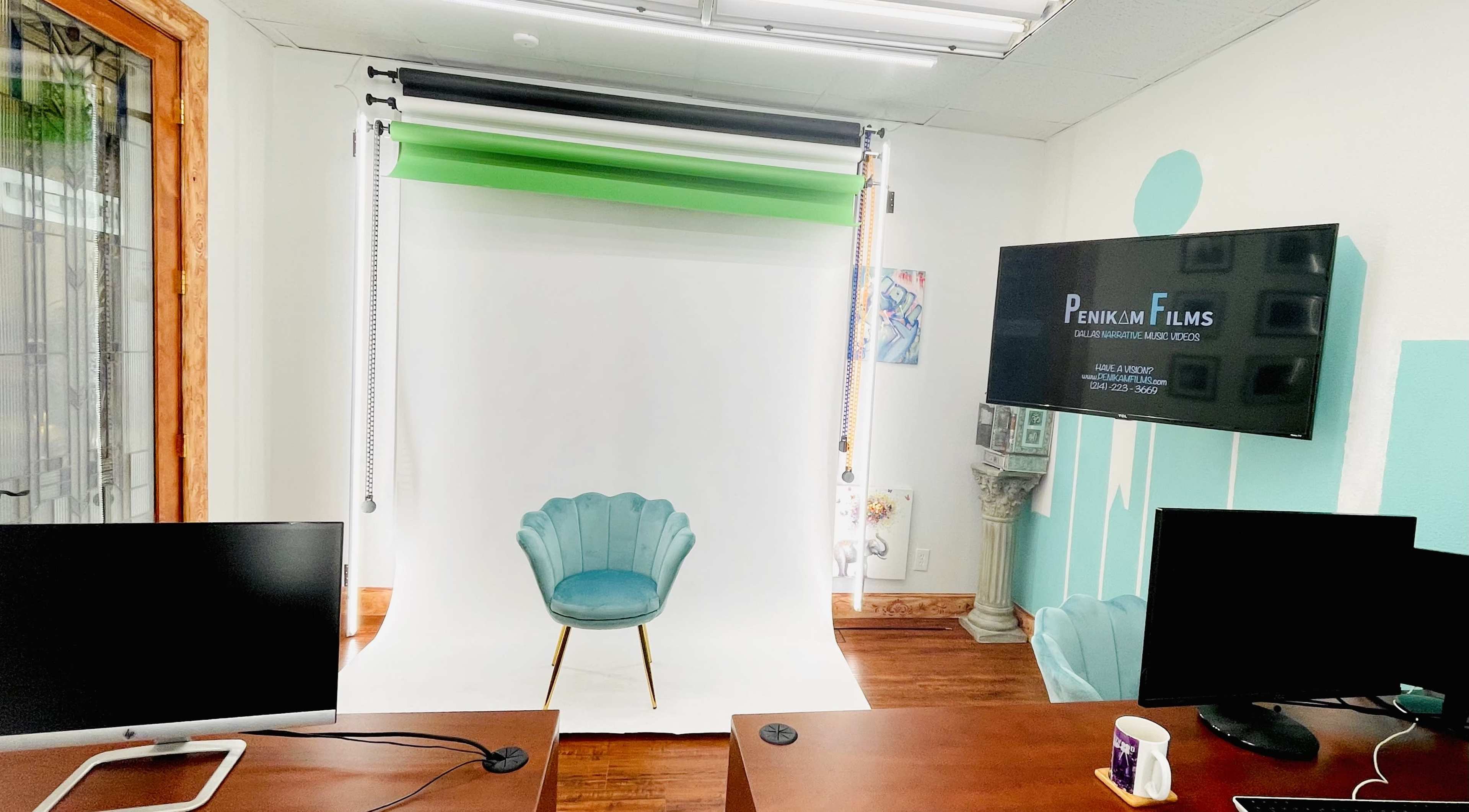 A photography studio setup featuring a green screen backdrop, a white backdrop, a teal chair, and a television displaying a logo for "Penlink Films."