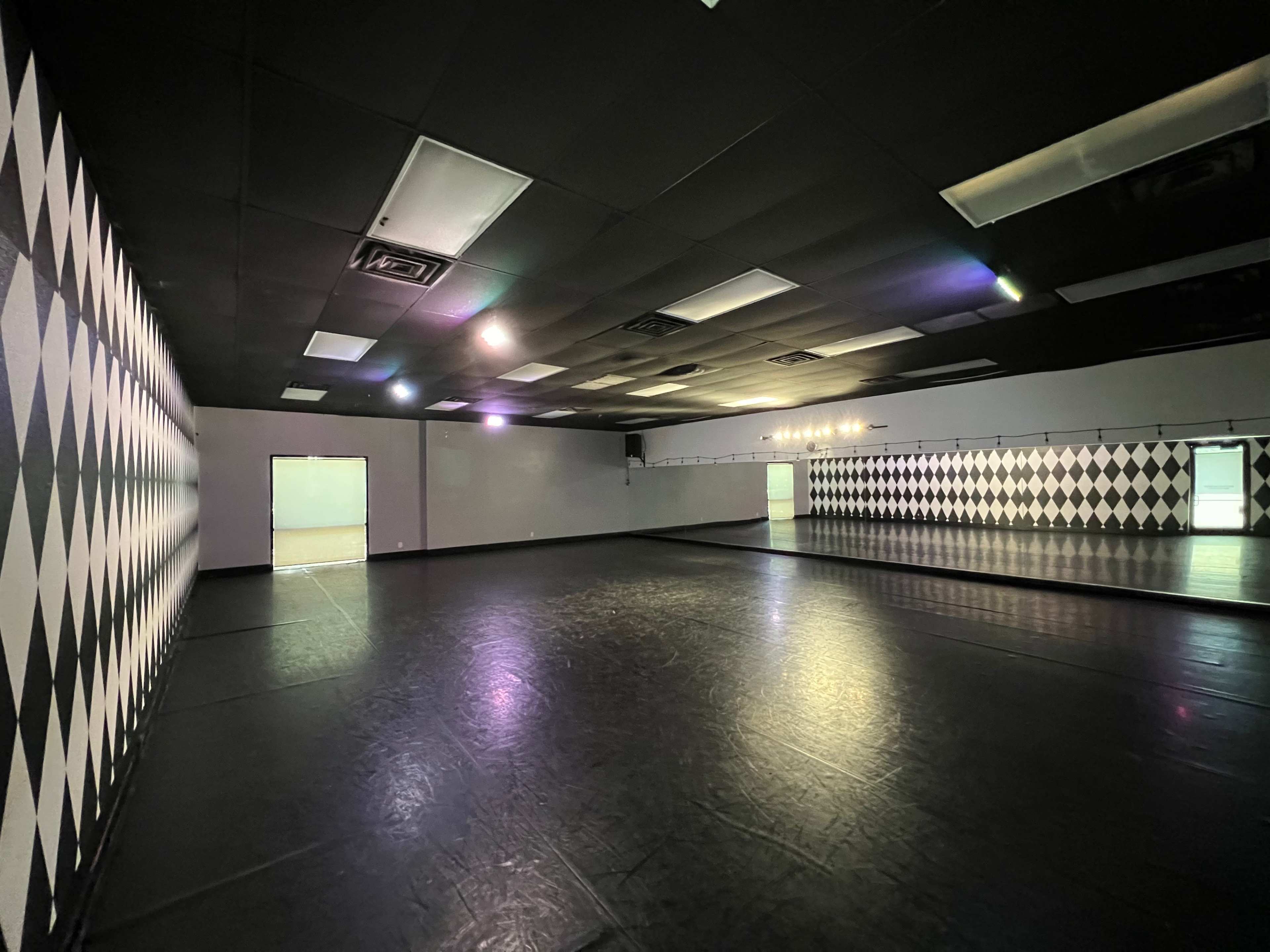 A spacious dance studio with black and white checkered walls and a large mirrored section.