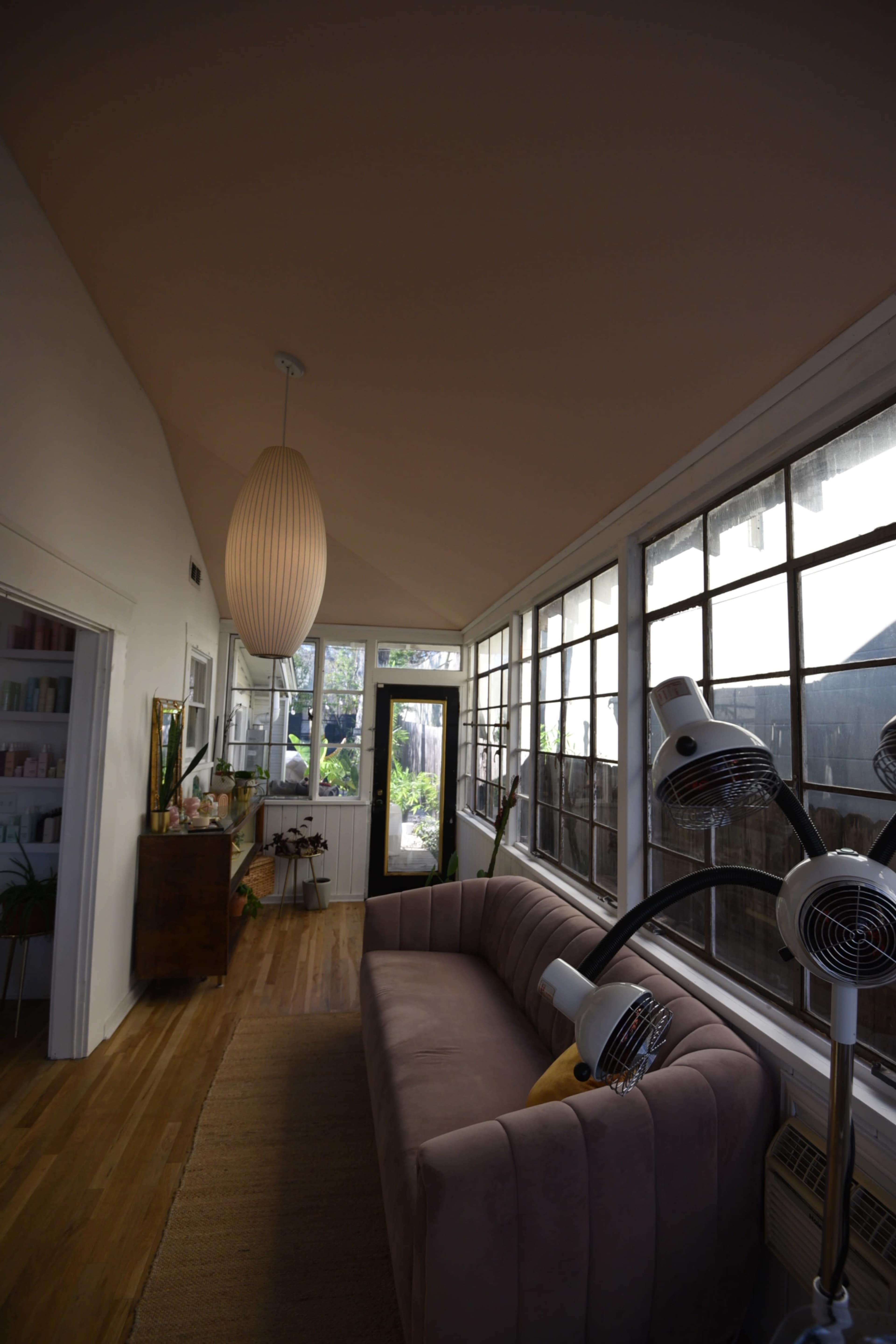 A cozy interior space with a gray sofa, large windows, and a pendant light.