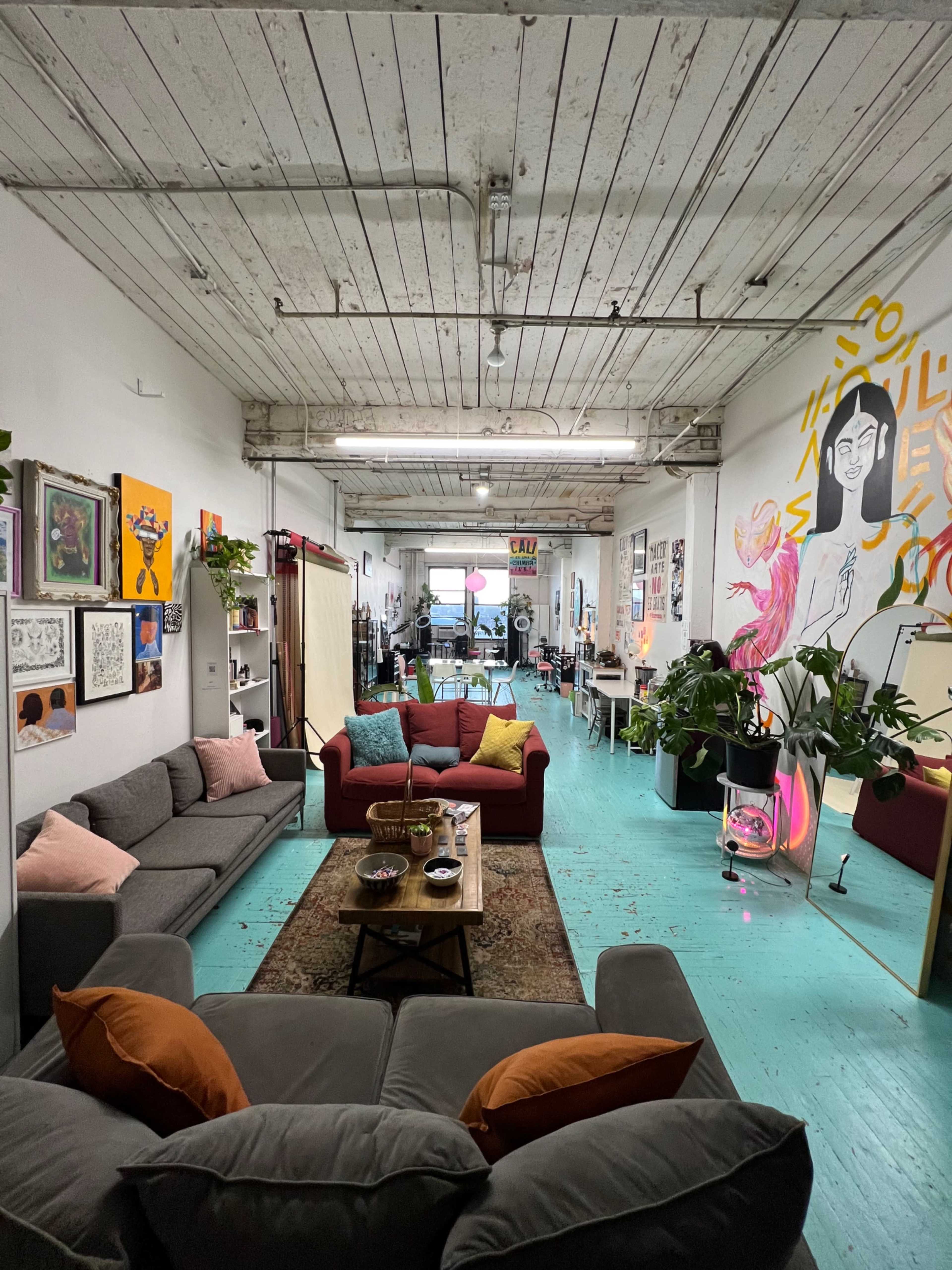 A spacious, brightly lit room with modern furniture, including two sofas, a coffee table, and vibrant wall art.