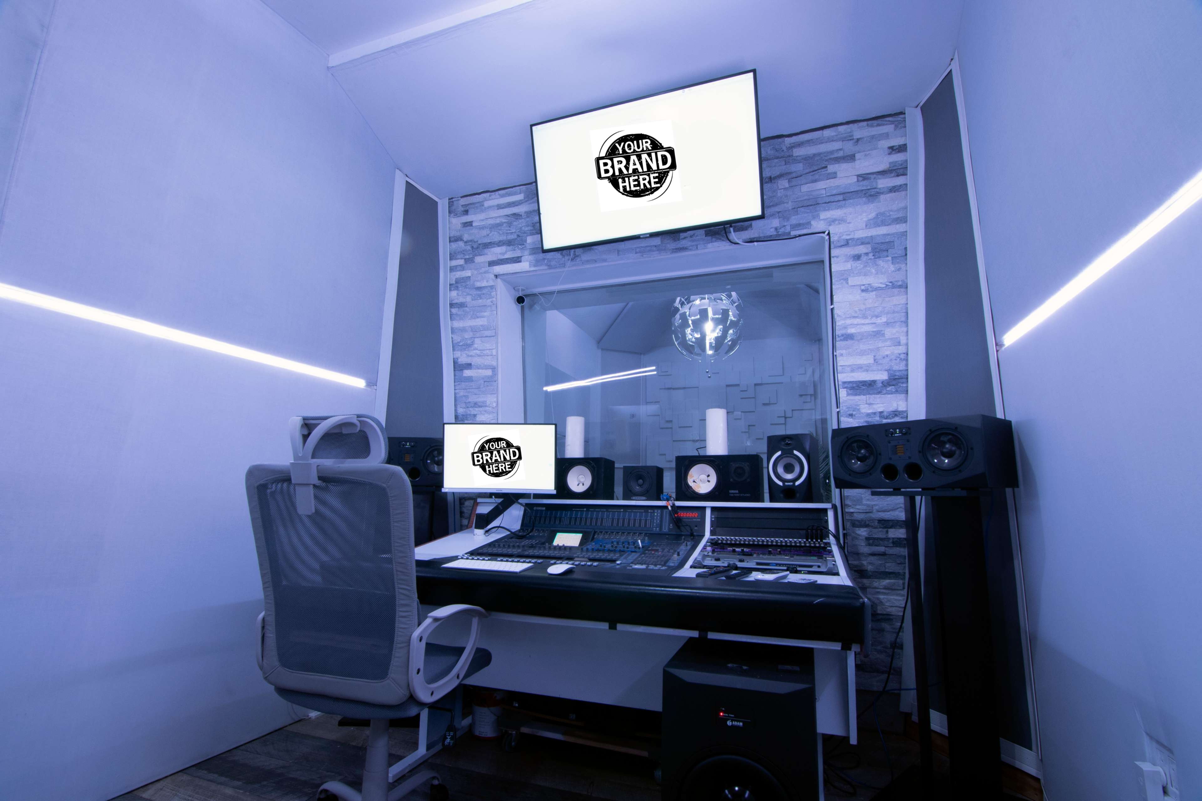A modern music studio with a mixing console, speakers, and screens displaying a placeholder for branding.