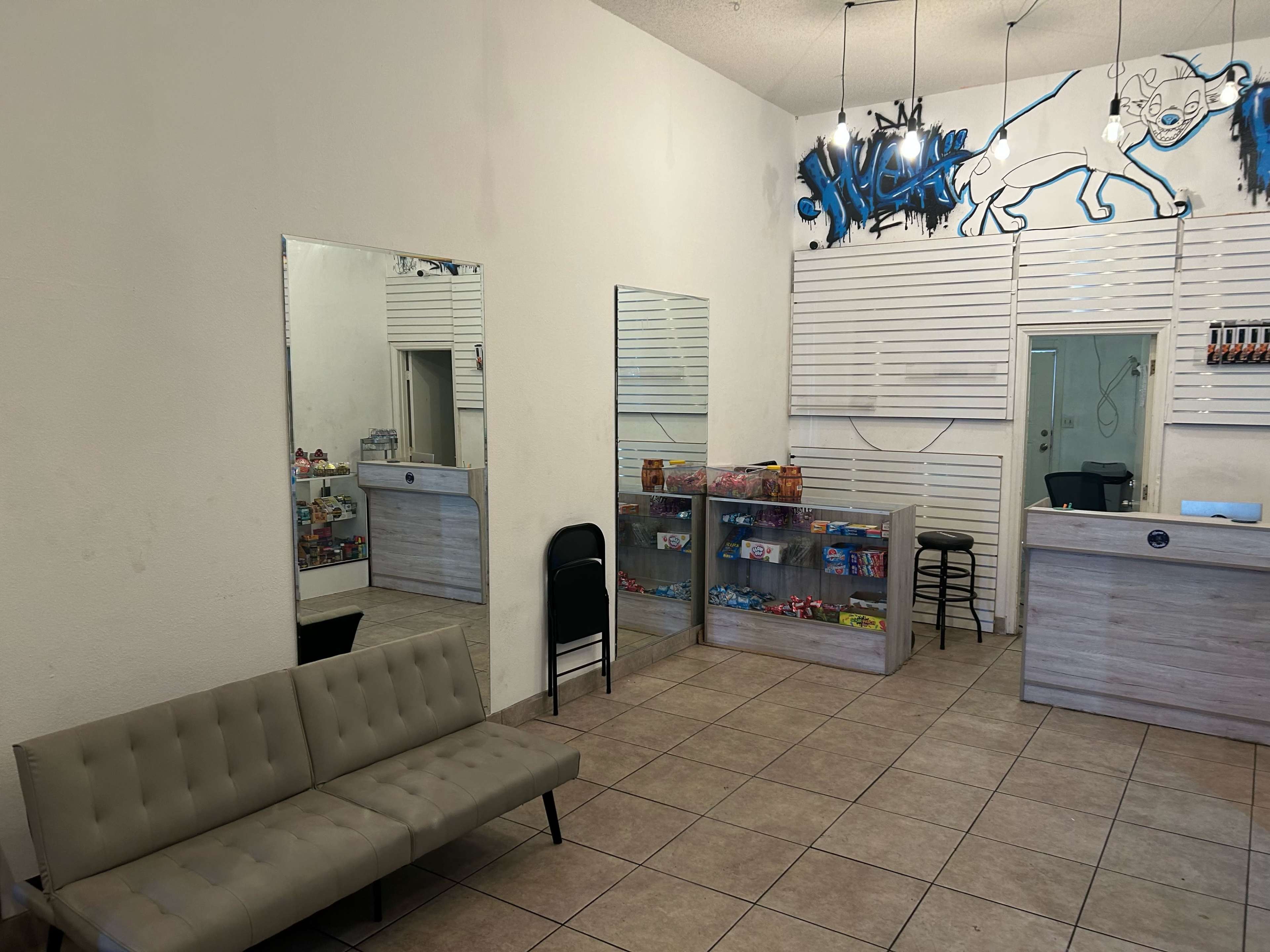 The image shows a small storefront interior with a seating area, display shelves filled with snacks, and a counter at the back.