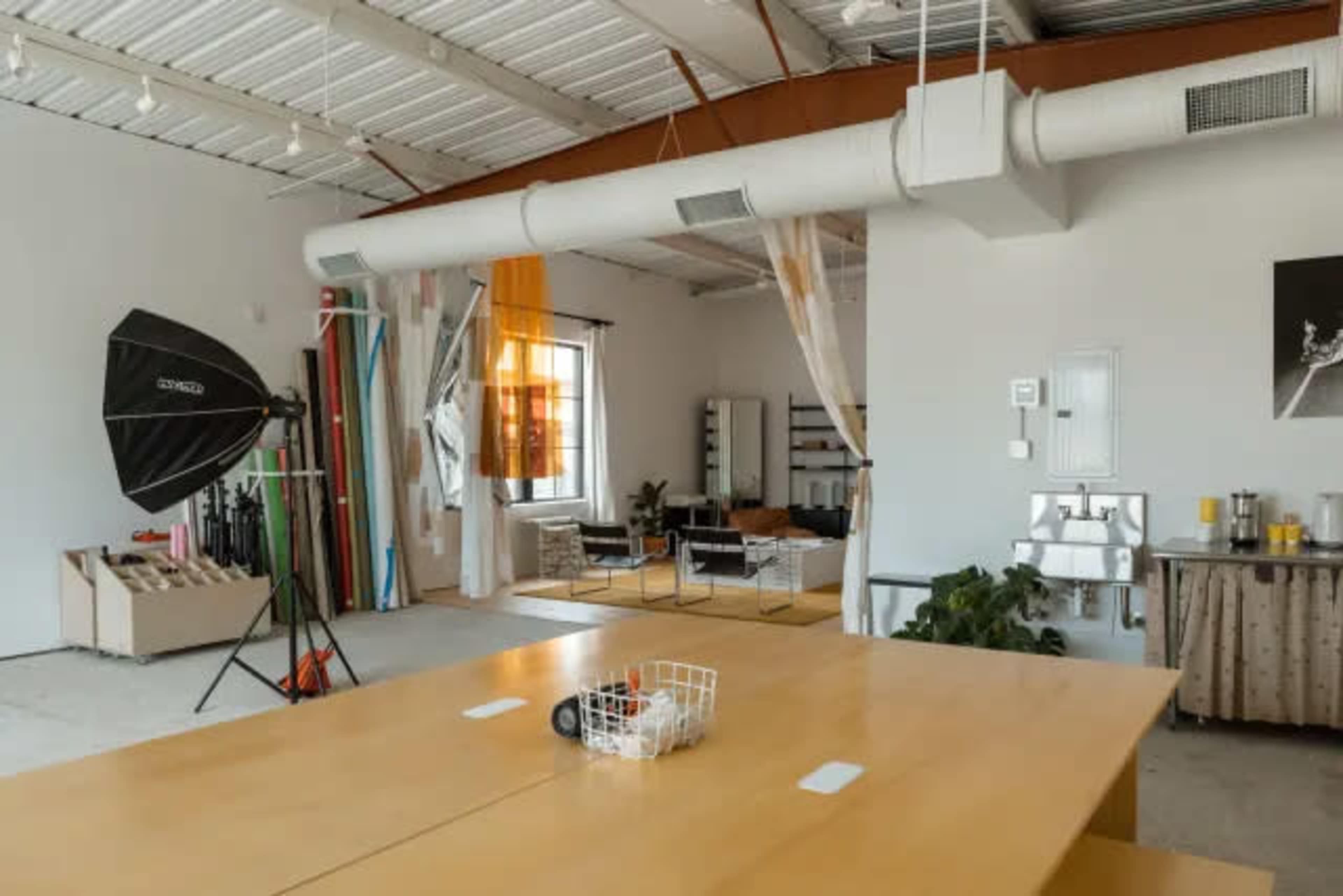 The image shows a spacious studio filled with various backdrops, seating, and photography equipment.