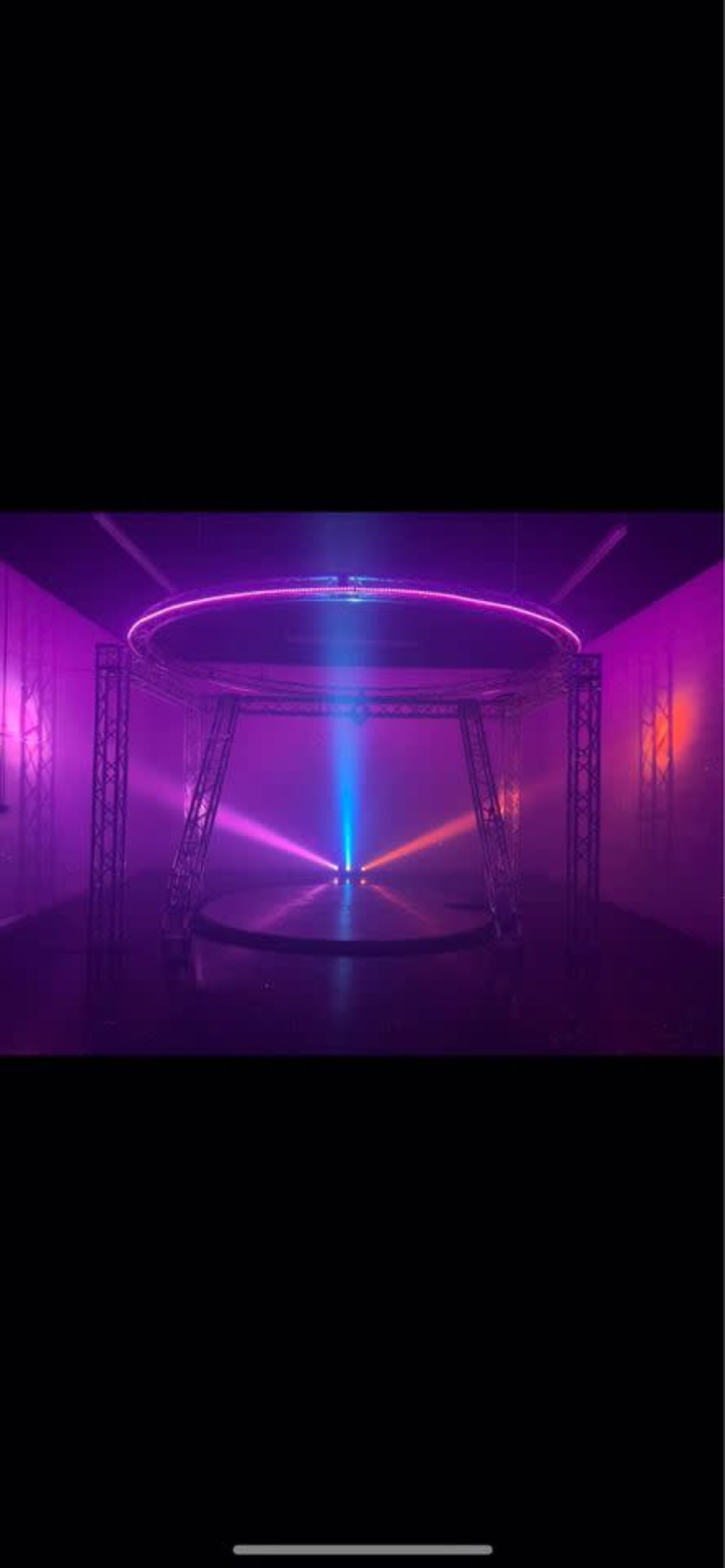 A circular structure with a glowing edge is surrounded by beams of light in a foggy space.