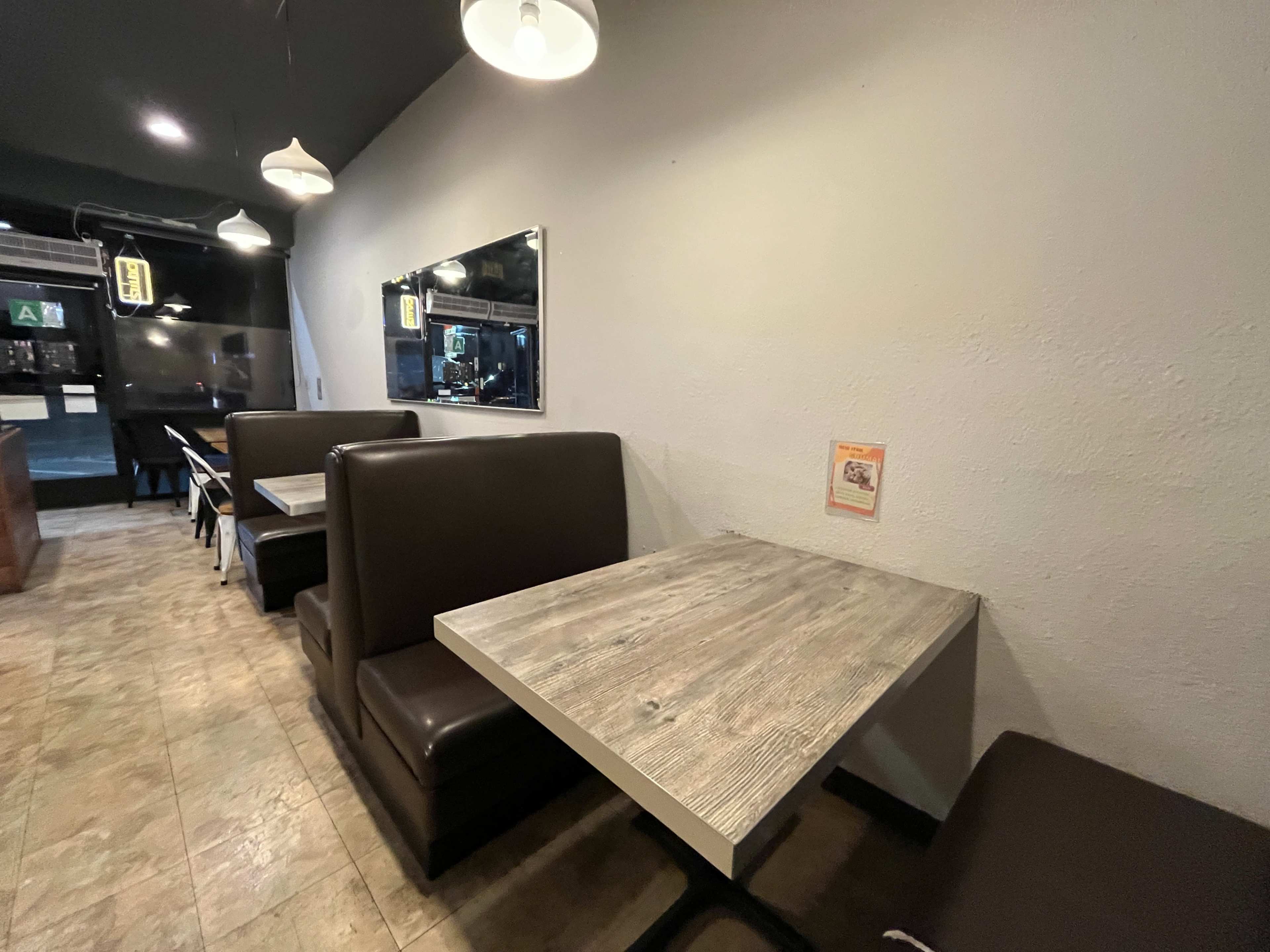 The image shows a cozy café interior with brown leather seating booths and wooden tables along a plain wall.