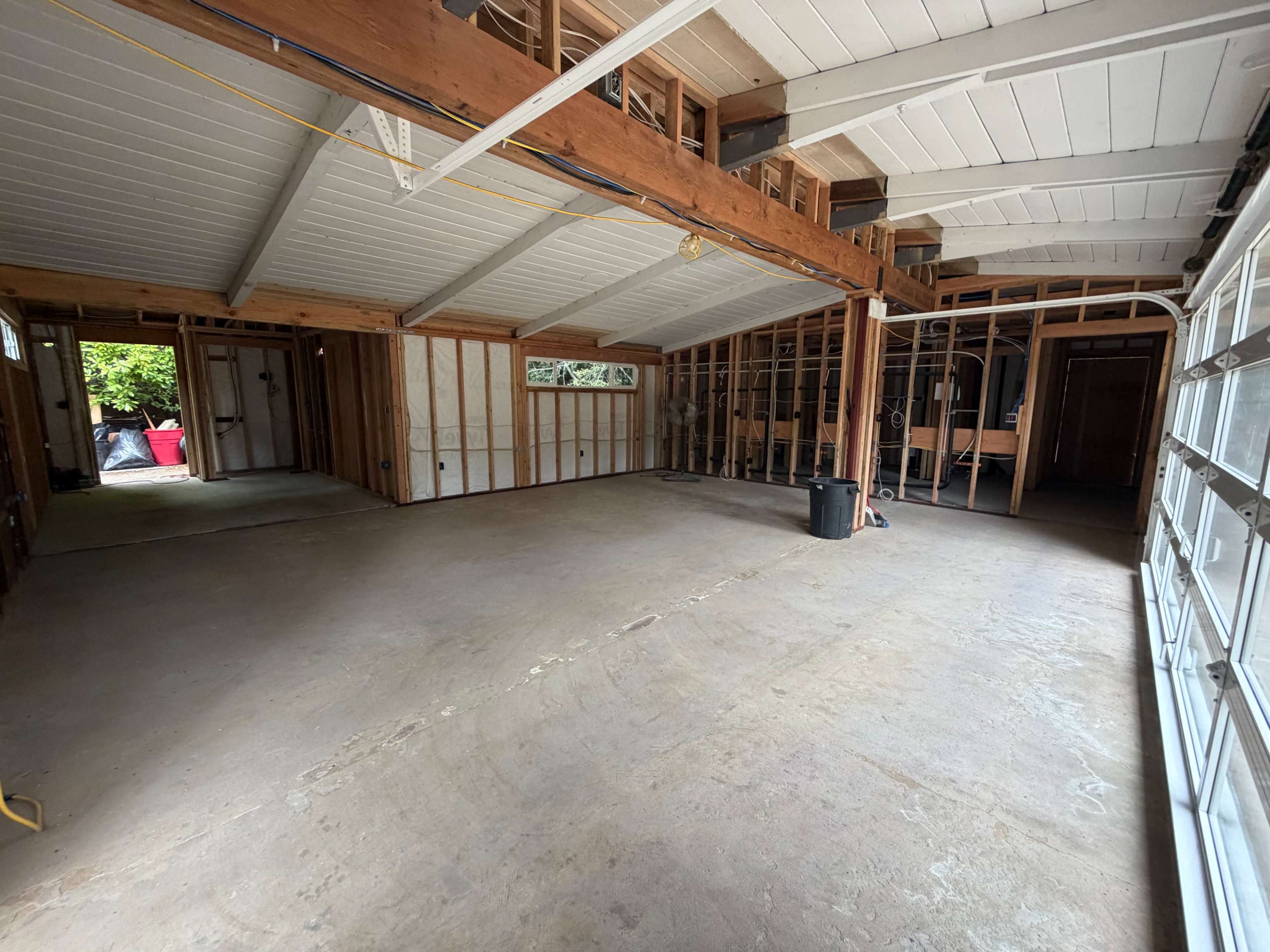 The image shows an unfinished garage interior with exposed framing and concrete flooring.