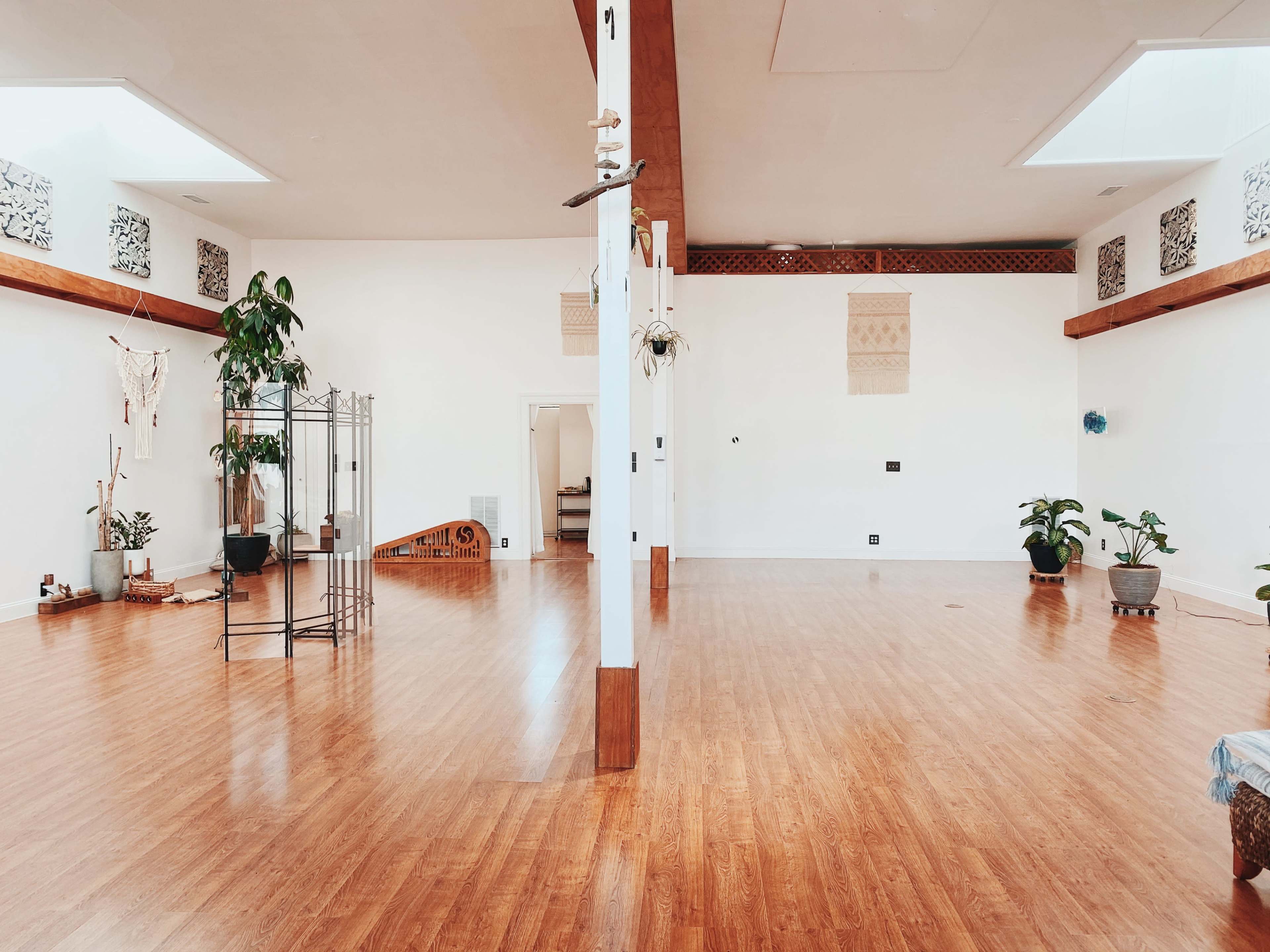 A spacious, empty room with wooden flooring, large skylights, and decorative elements along the walls.