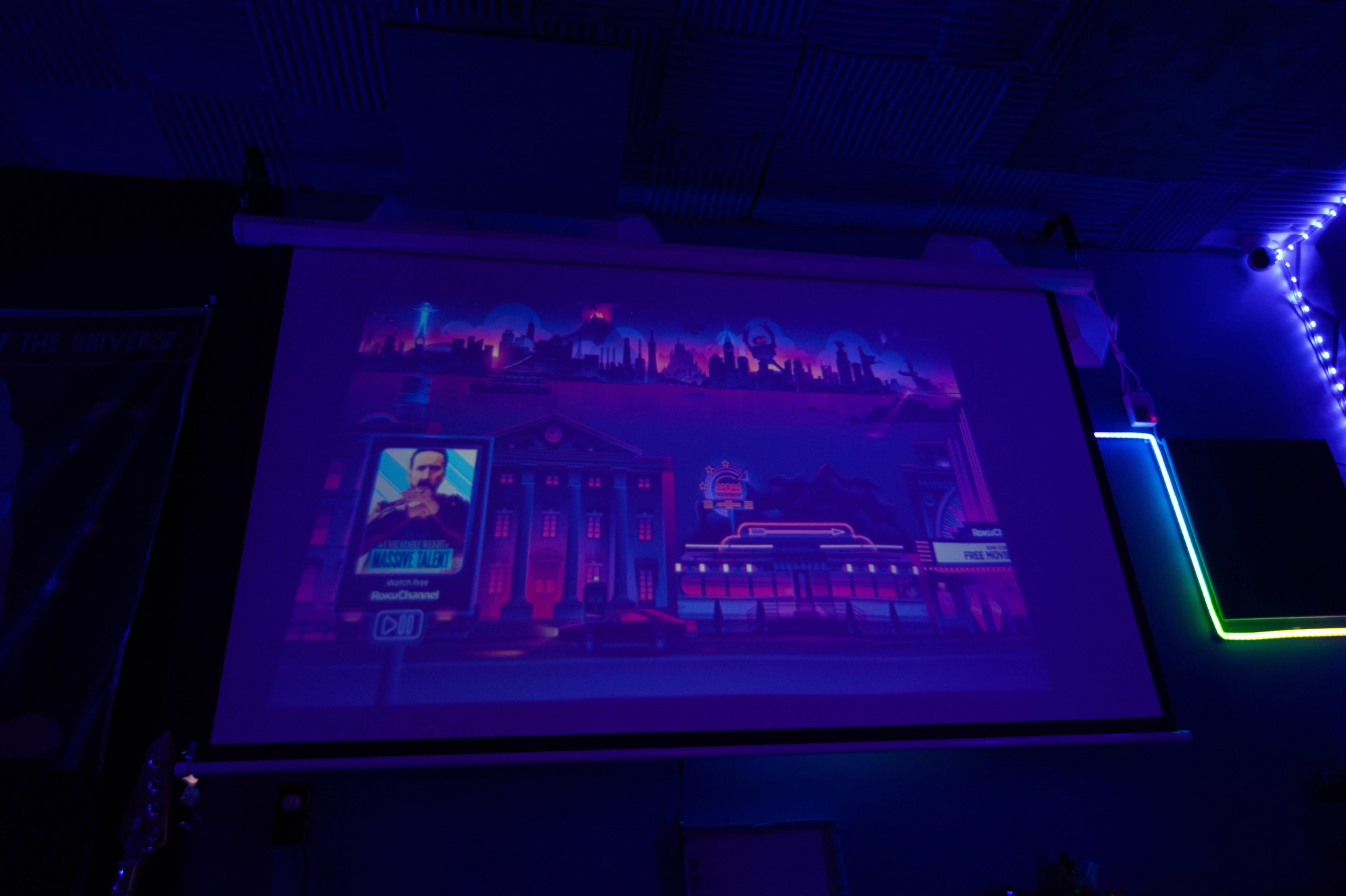 A colorful digital illustration is projected onto a screen, depicting a city skyline with futuristic buildings and neon elements.