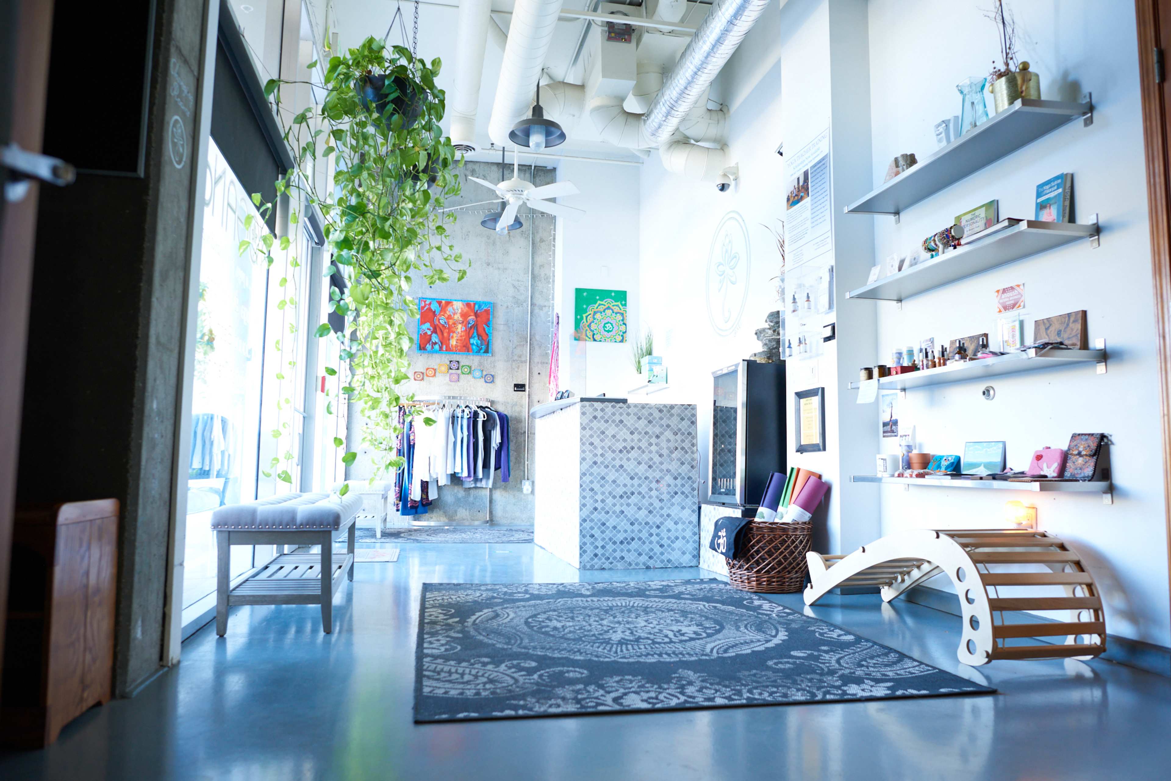 A modern, open interior space with a reception area, clothing display, and decorative plants.