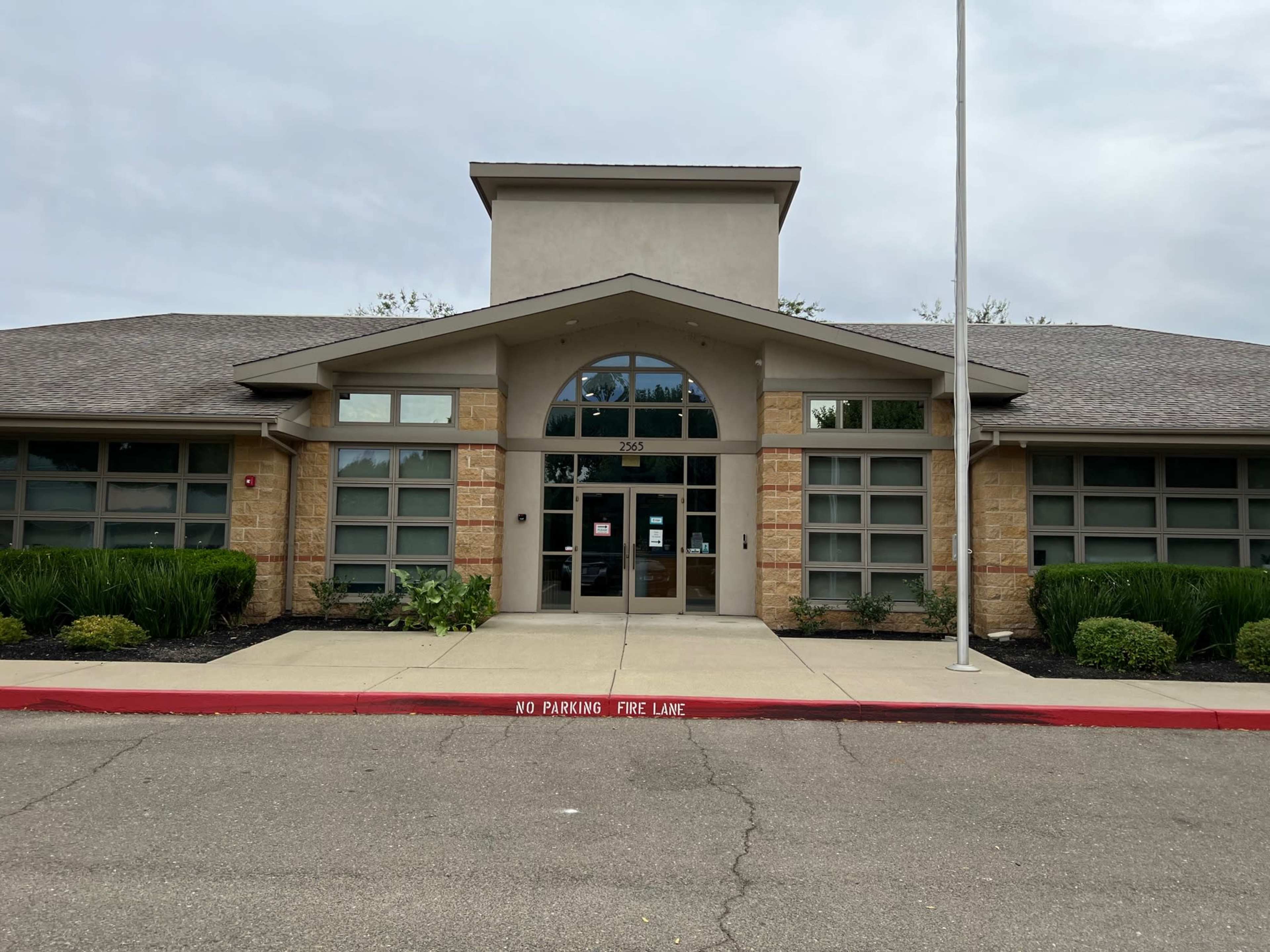 A single-story building with a central entrance, large windows, and a landscaped front area.